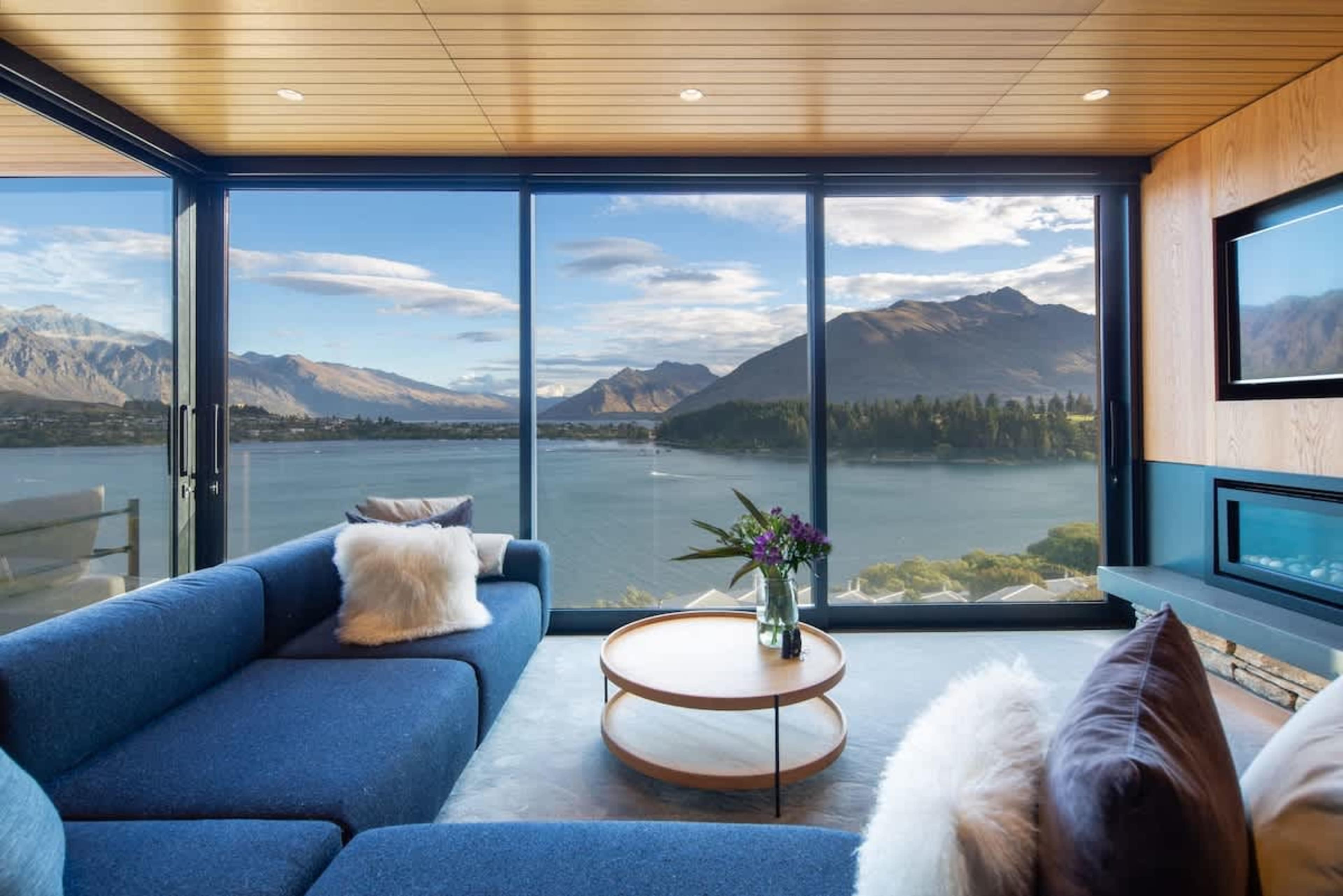 Cozy Living Room with Fireplace and Lake Views – Relax in this inviting living area with a beautiful fireplace, creating a warm, serene atmosphere. Enjoy stunning views of Lake Wakatipu and the surrounding mountains from this elegant space.