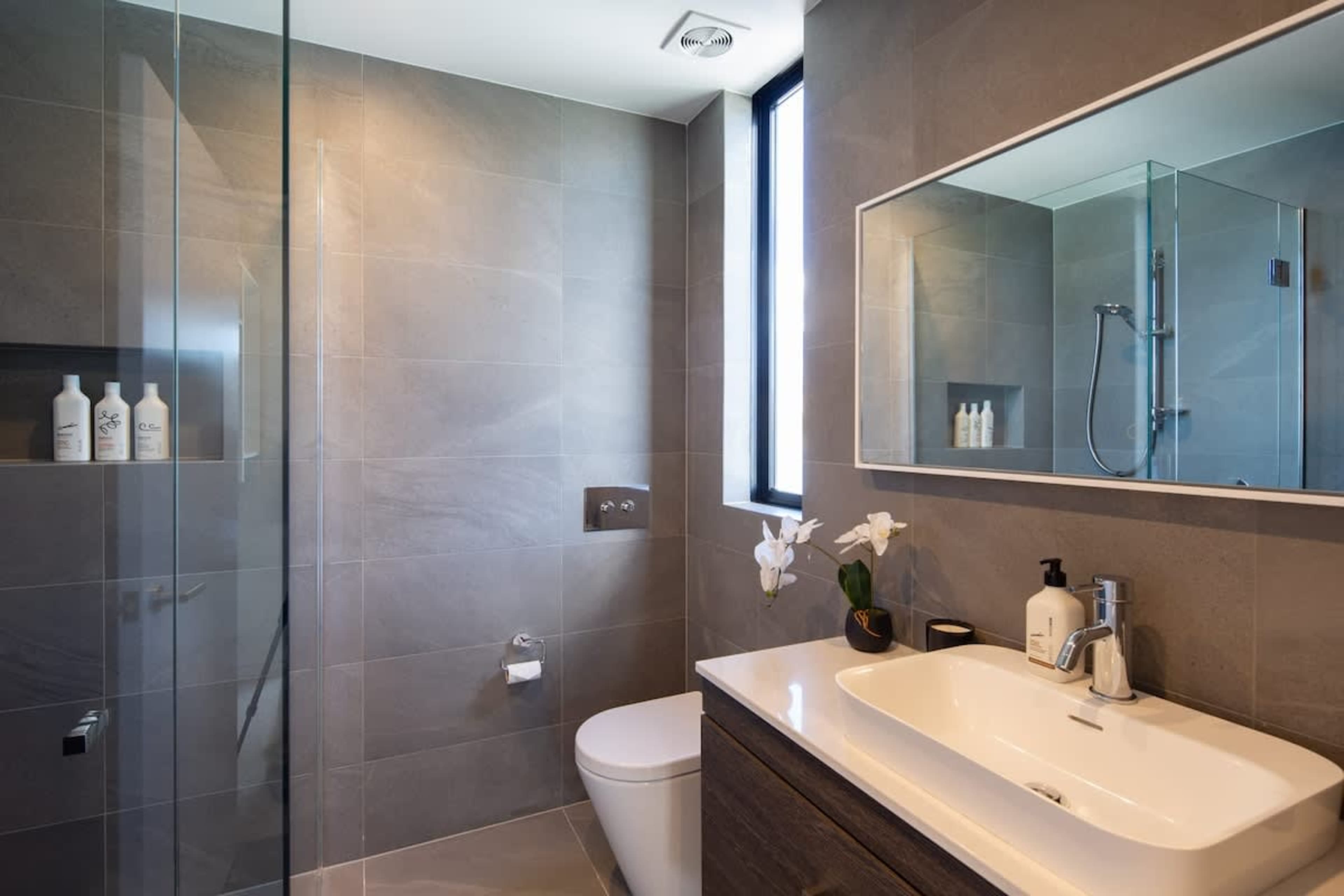 Stylish Second Bathroom – This modern bathroom features a spacious shower, sleek fixtures, and premium Ashley & Co toiletries, offering both comfort and luxury for your stay.