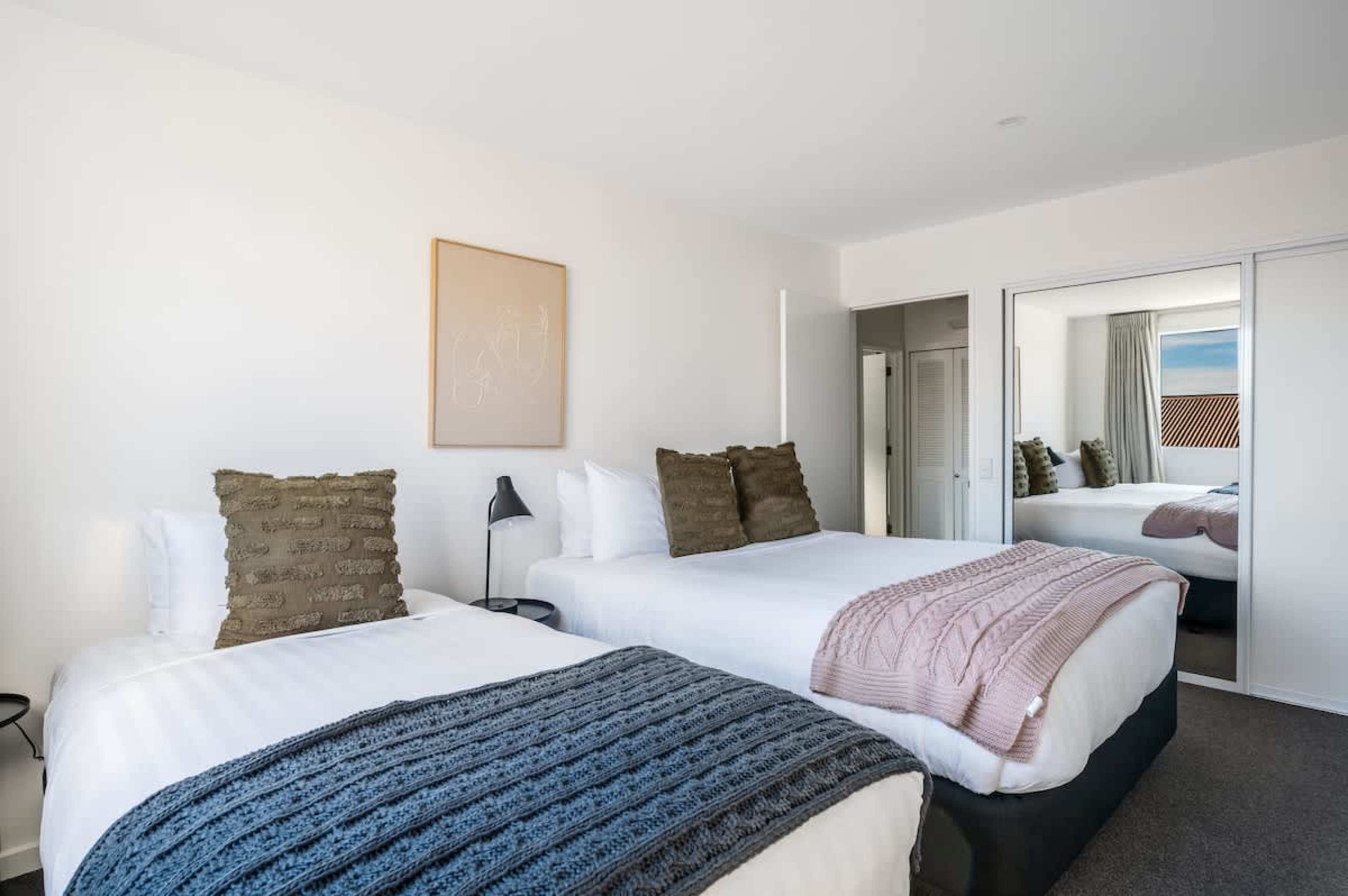 Cozy bedroom with queen and single beds, offering ample storage—perfect for your Queenstown stay, with room for all your gear and essentials.