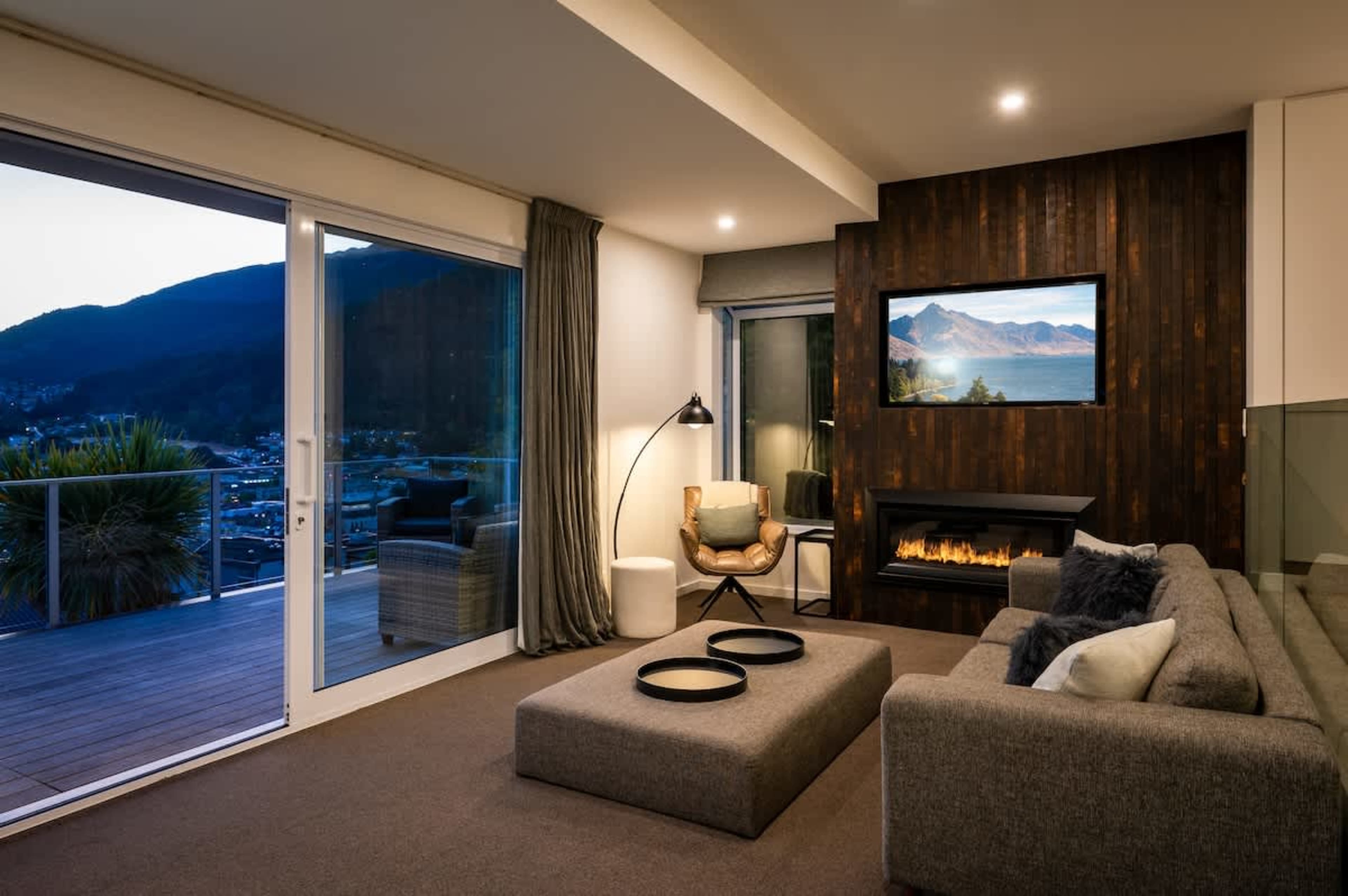 Spacious living room with gas fireplace, large flat-screen TV with Netflix, and breathtaking Lake Wakatipu views—perfect for cozy family nights in Queenstown.