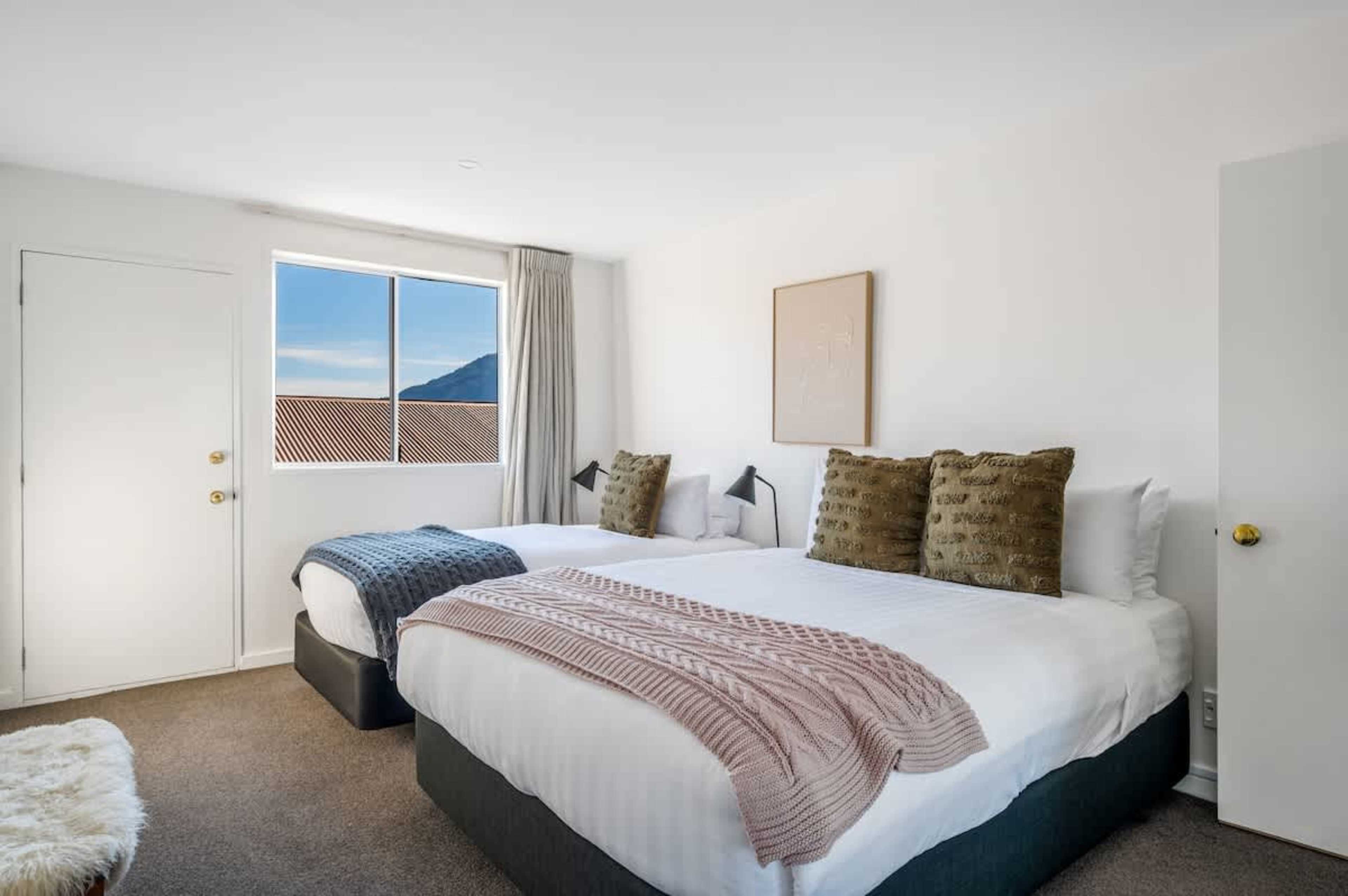 Spacious Queenstown bedroom with queen and single beds—ideal for families or groups, with ample storage for ski gear or shopping.