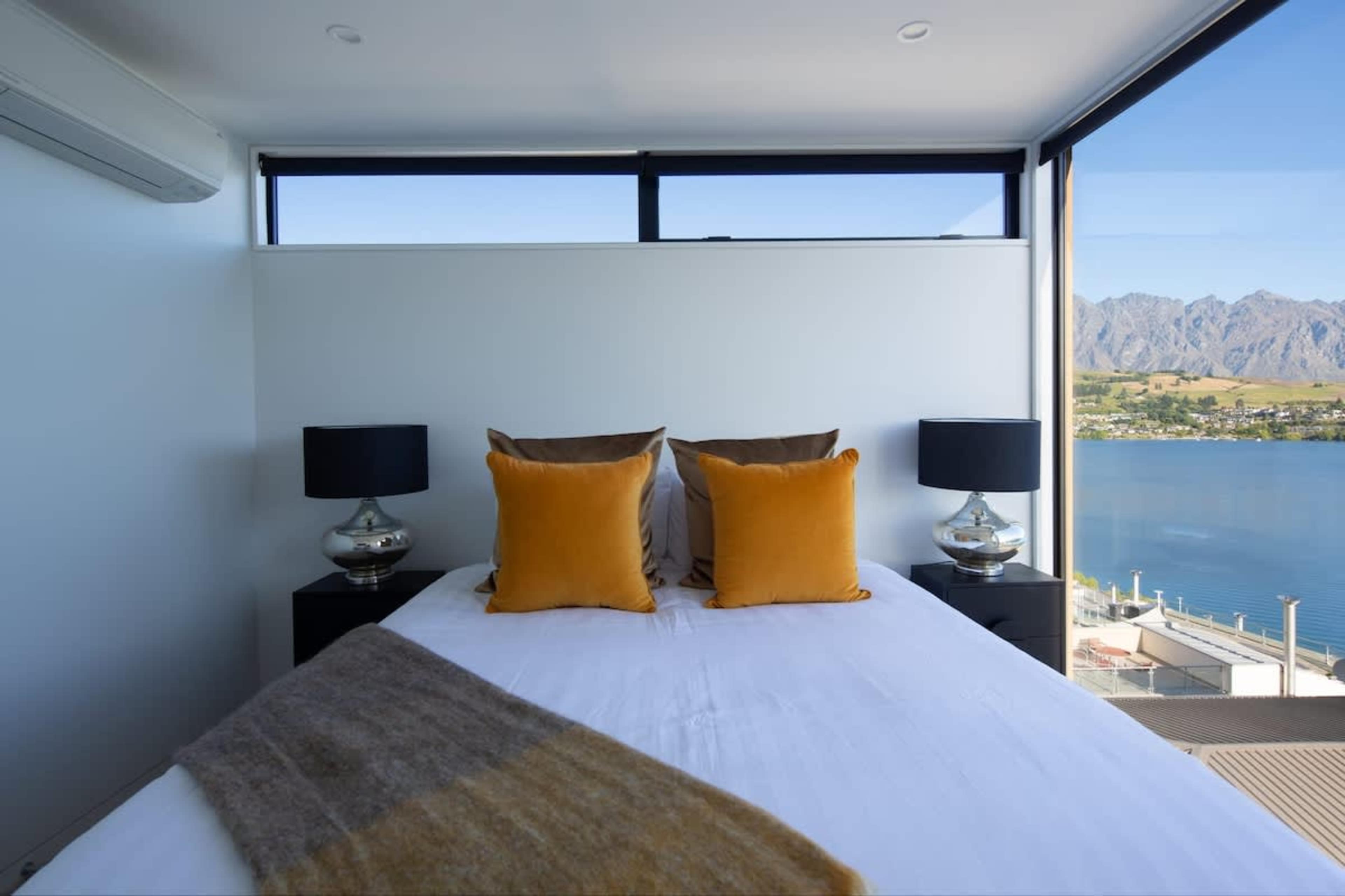 This spacious second master bedroom features a luxurious king-sized bed, a sleek ensuite with high-end finishes, and a walk-in wardrobe. Expansive windows offer spectacular lake and mountain views, creating a serene and private retreat.