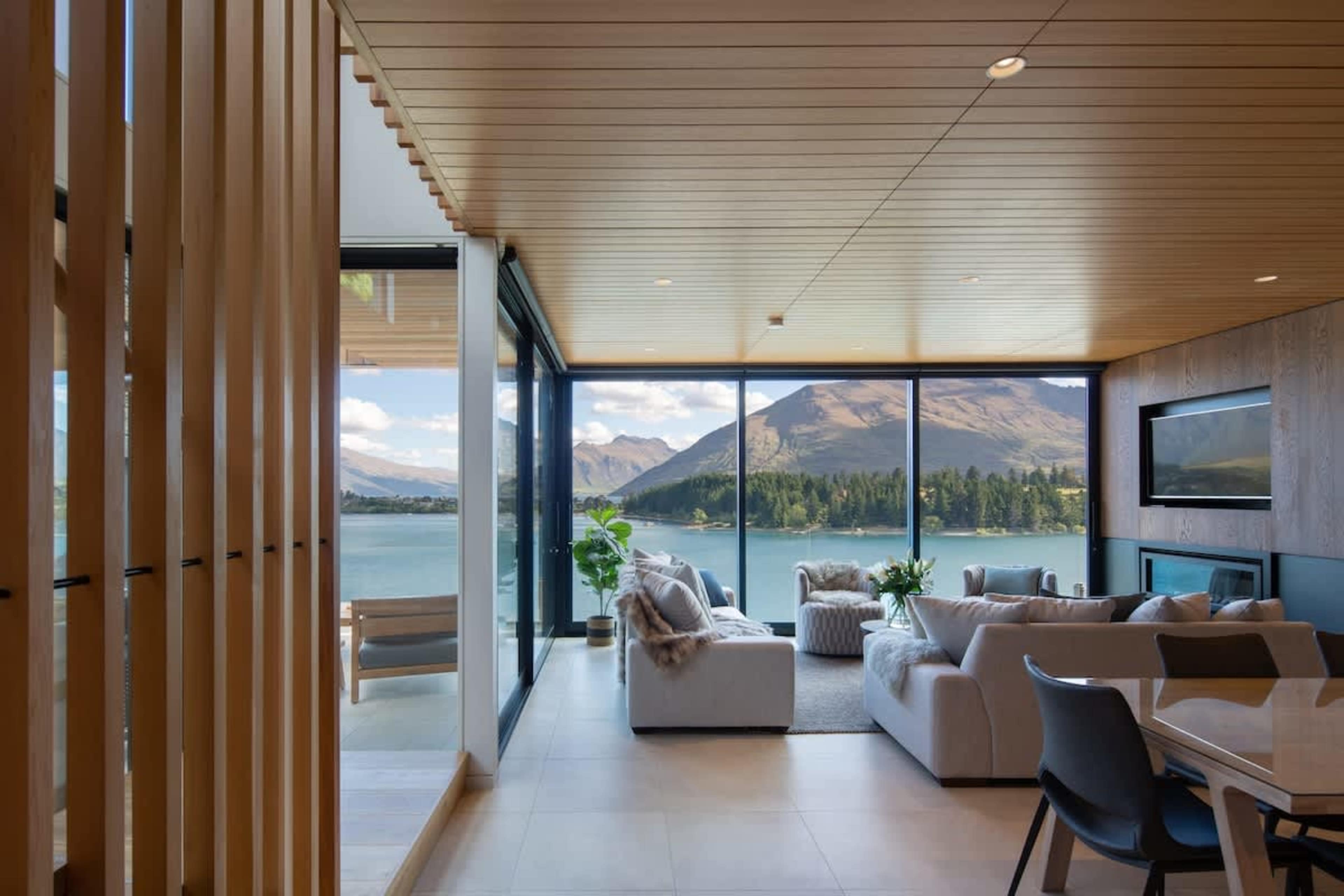 Enjoy endless views of the lake and Remarkables mountains from this stylish living room. A gas fireplace and air conditioning ensure comfort in any season, while the contemporary design enhances the space’s charm.