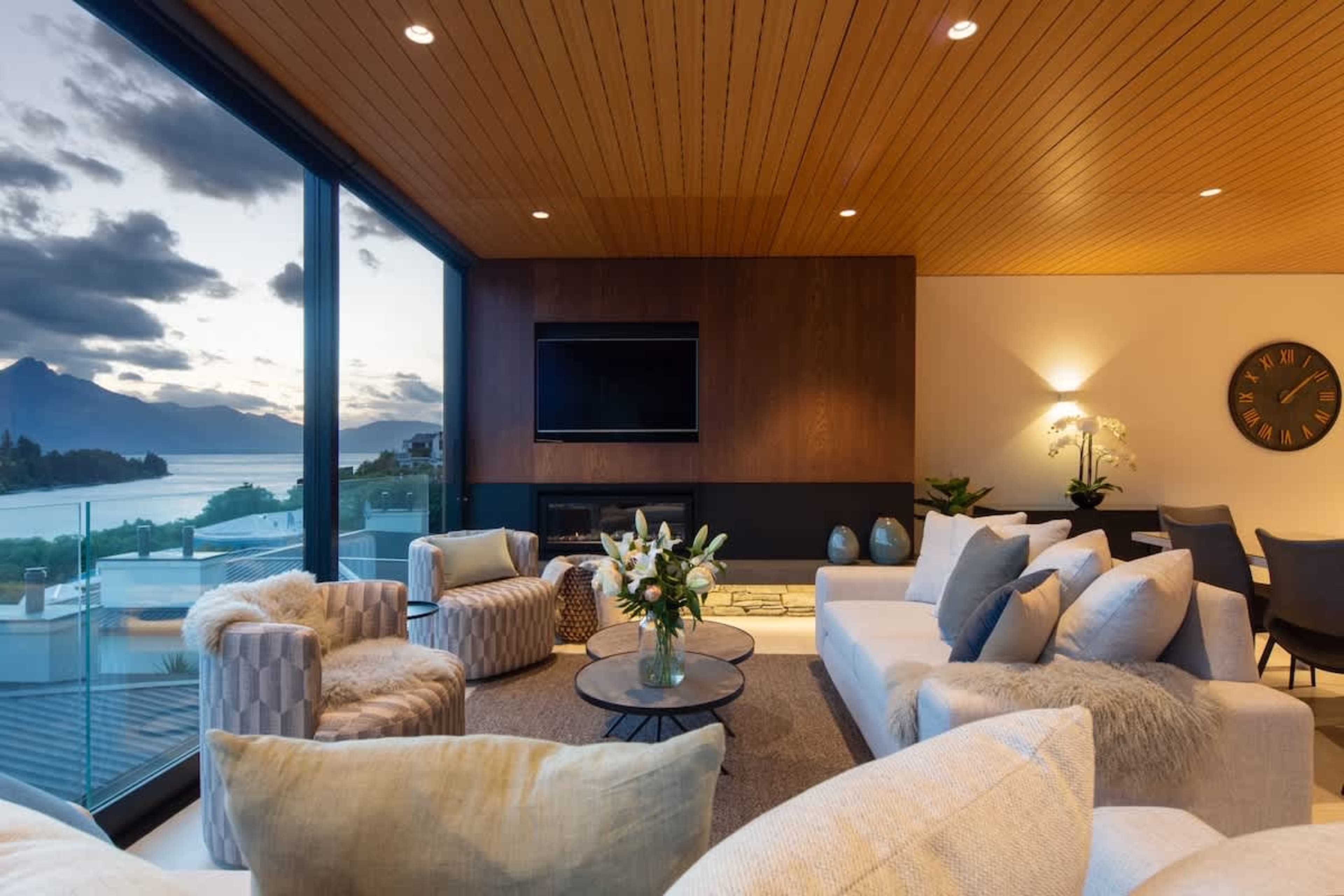 A luxurious retreat featuring a cozy gas fireplace, AC, and large windows framing lake and mountain views. The blend of contemporary decor and serene surroundings makes it a perfect spot to relax.