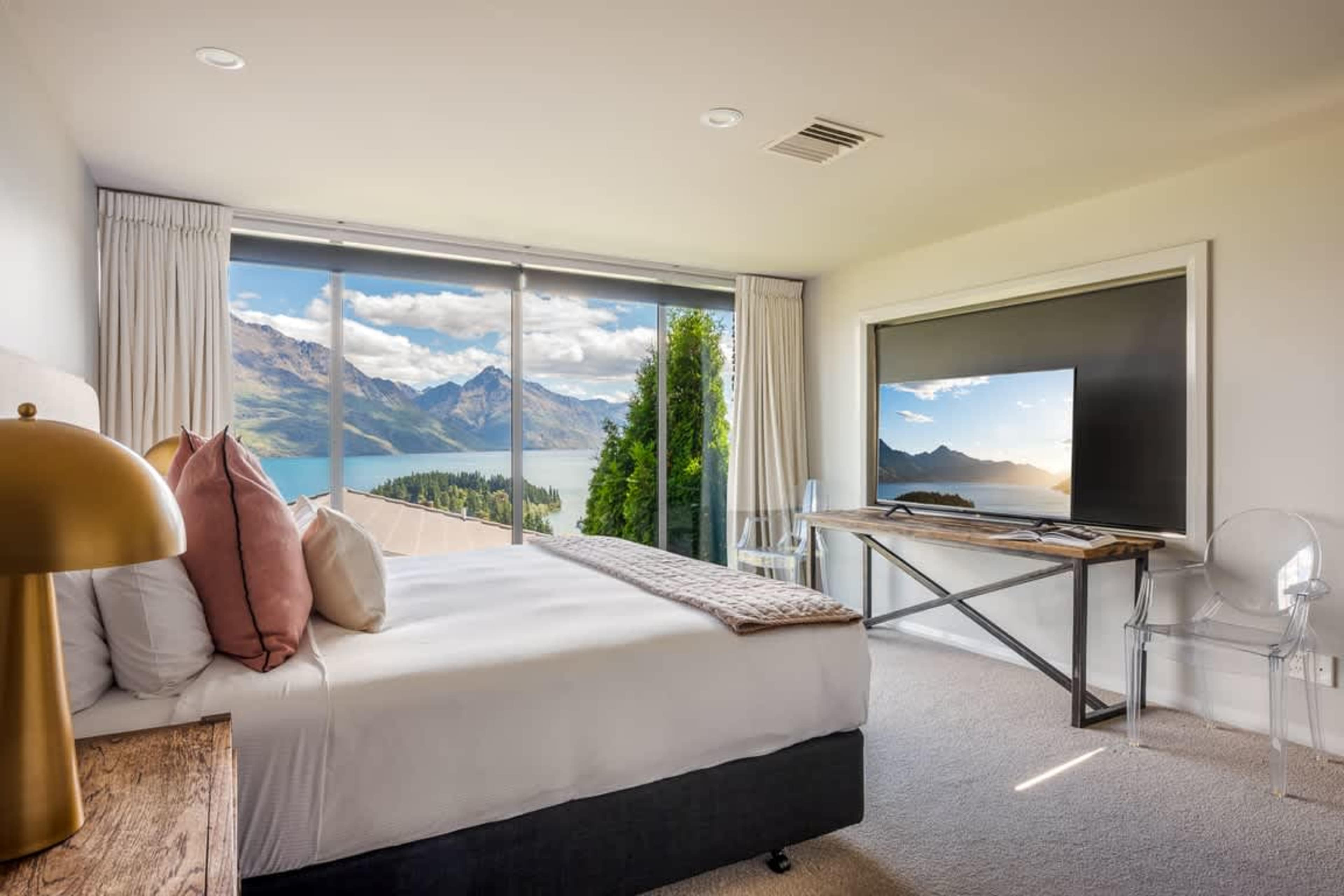 Private Oasis Unwind in the master suite with floor-to-ceiling windows showcasing Queenstown’s iconic scenery and a luxurious ensuite bathroom.