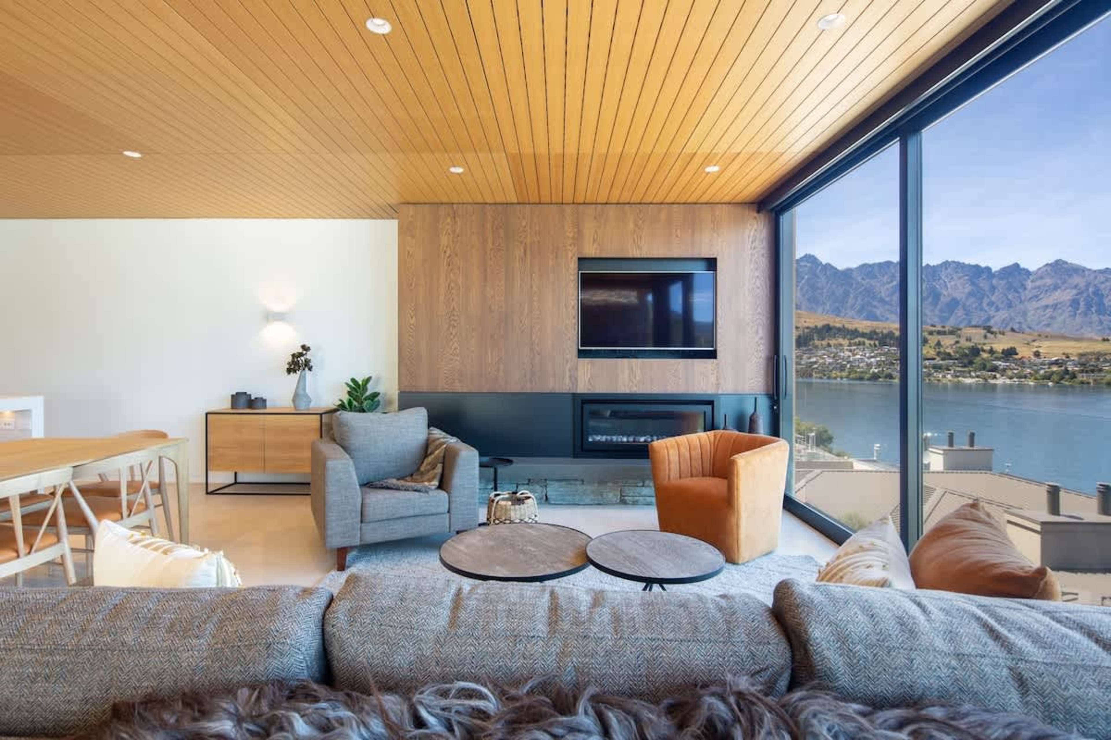 Relax in this airy, open-plan living room with high ceilings and seamless indoor-outdoor flow. Take in the breathtaking panoramic views of Lake Wakatipu and Queenstown's stunning mountains from the comfort of this spacious villa.