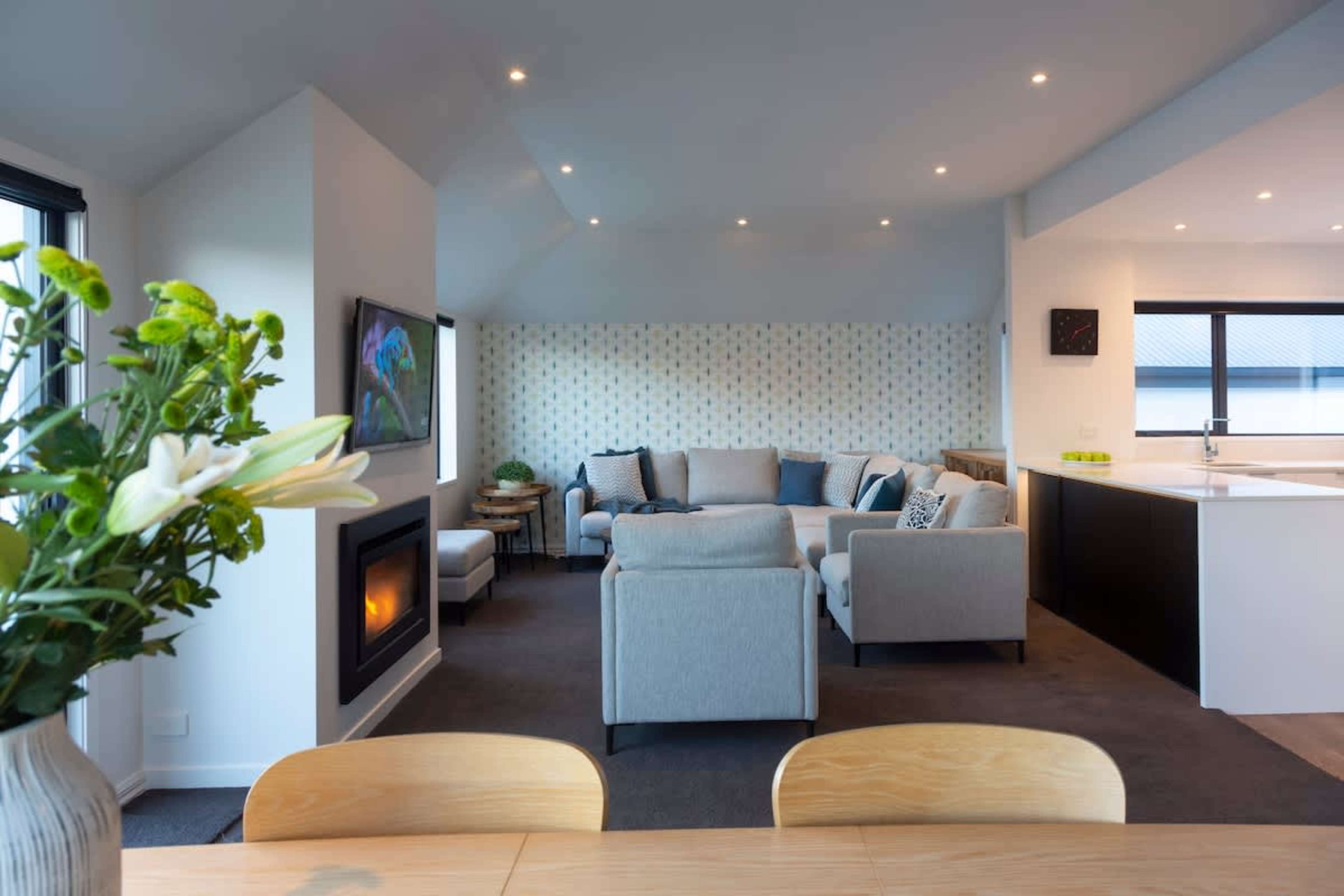 Cozy Family Space: Gather with loved ones in this stylish living room, complete with plush seating, AC, and a gas fireplace, all framed by spectacular Queenstown views.