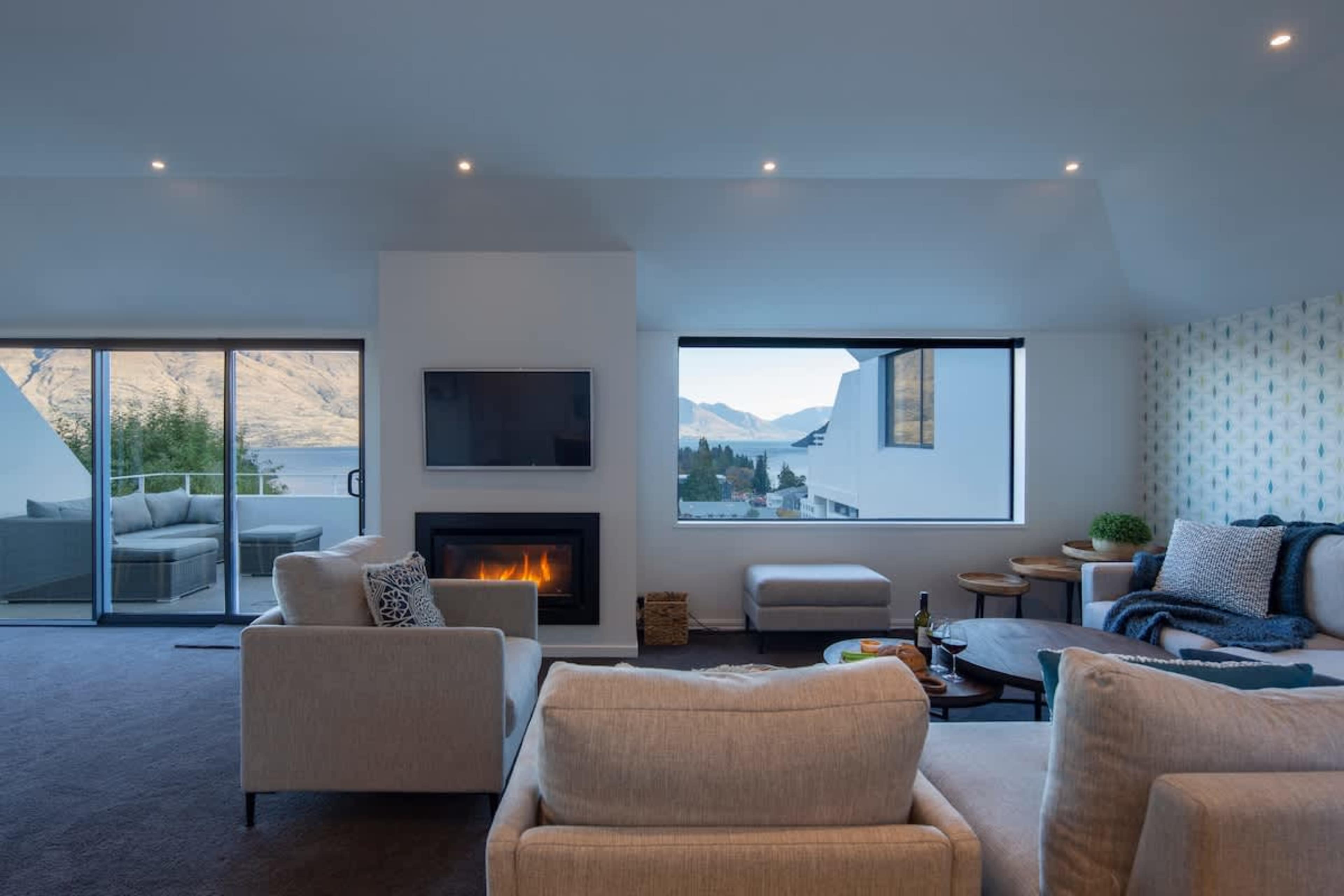 Luxury and Comfort Combined: This open-plan living room offers uninterrupted views, a warming gas fireplace, and AC for the perfect retreat after exploring Queenstown.