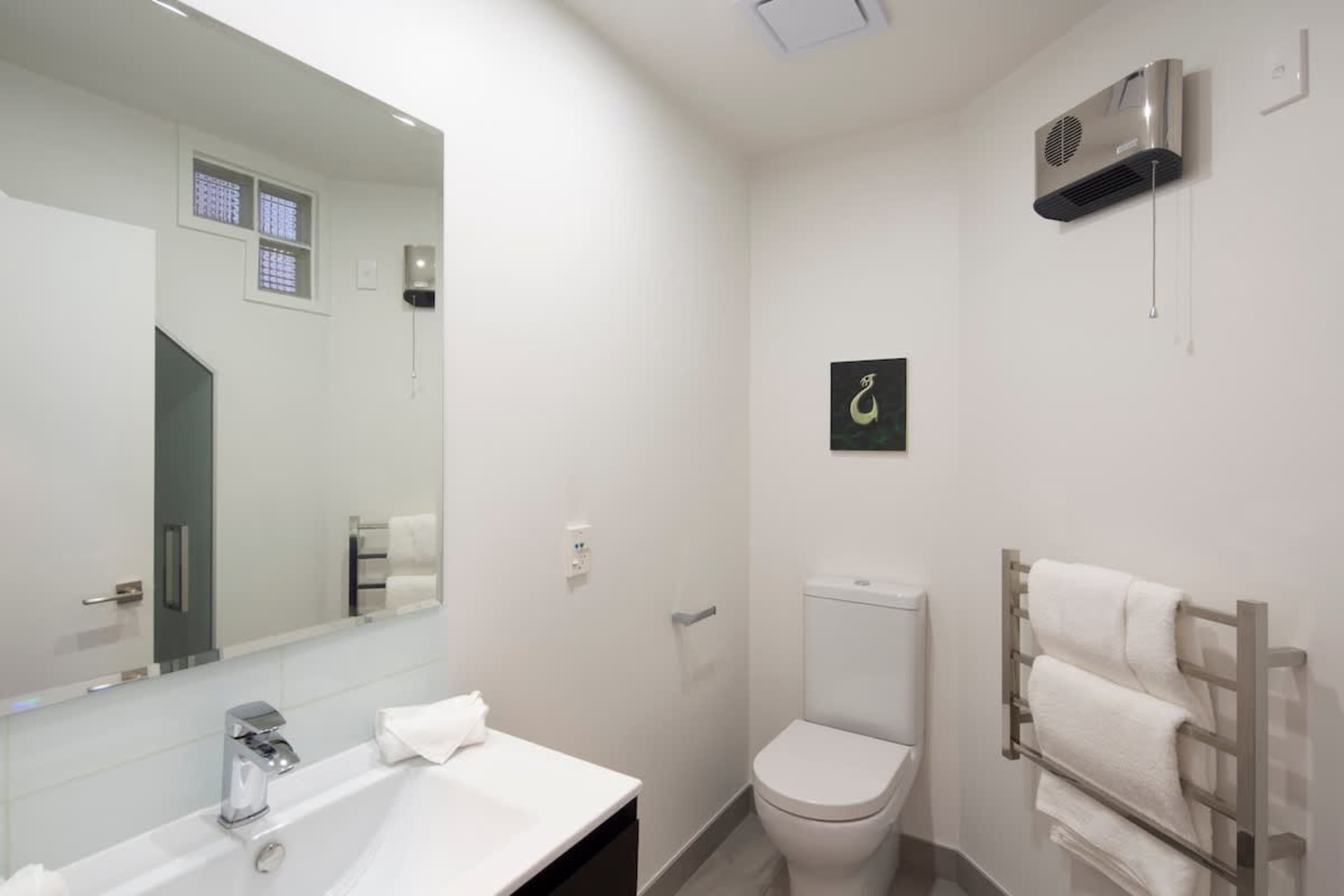 Contemporary Convenience: The second bathroom offers a sleek design, a spacious shower, and warm towel rails, ensuring comfort and functionality for all guests.