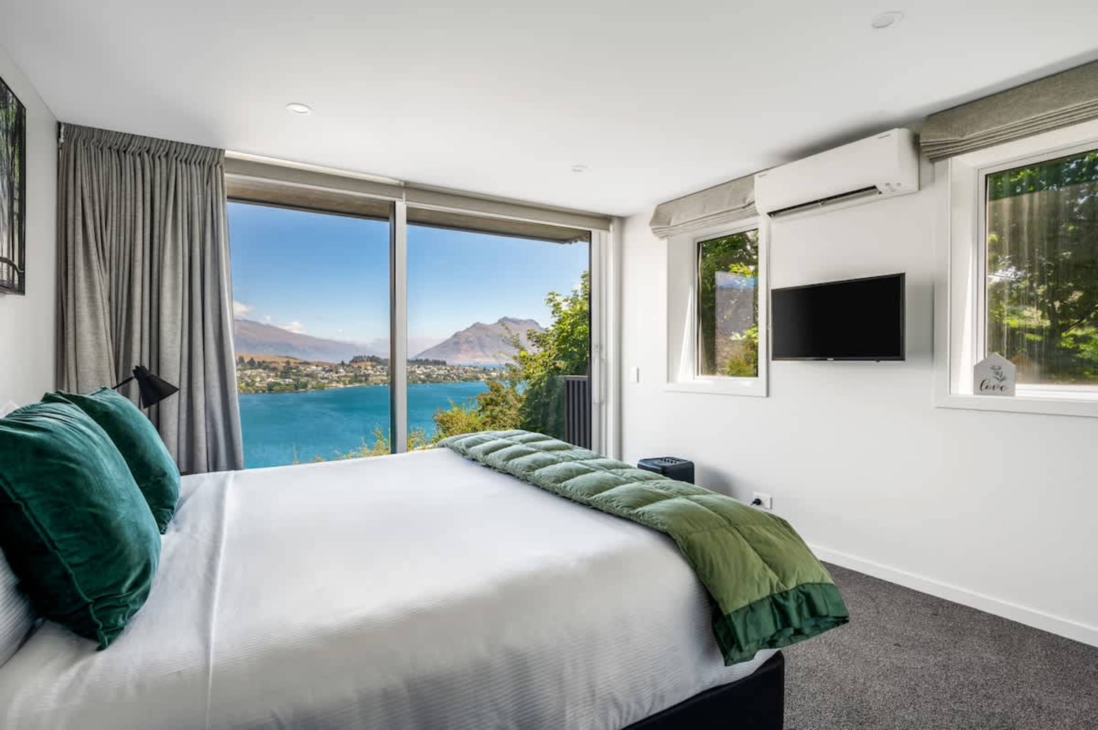 This luxurious master bedroom includes a king-sized bed, a private ensuite with a walk-in shower, and large windows framing breathtaking views, creating a serene retreat.