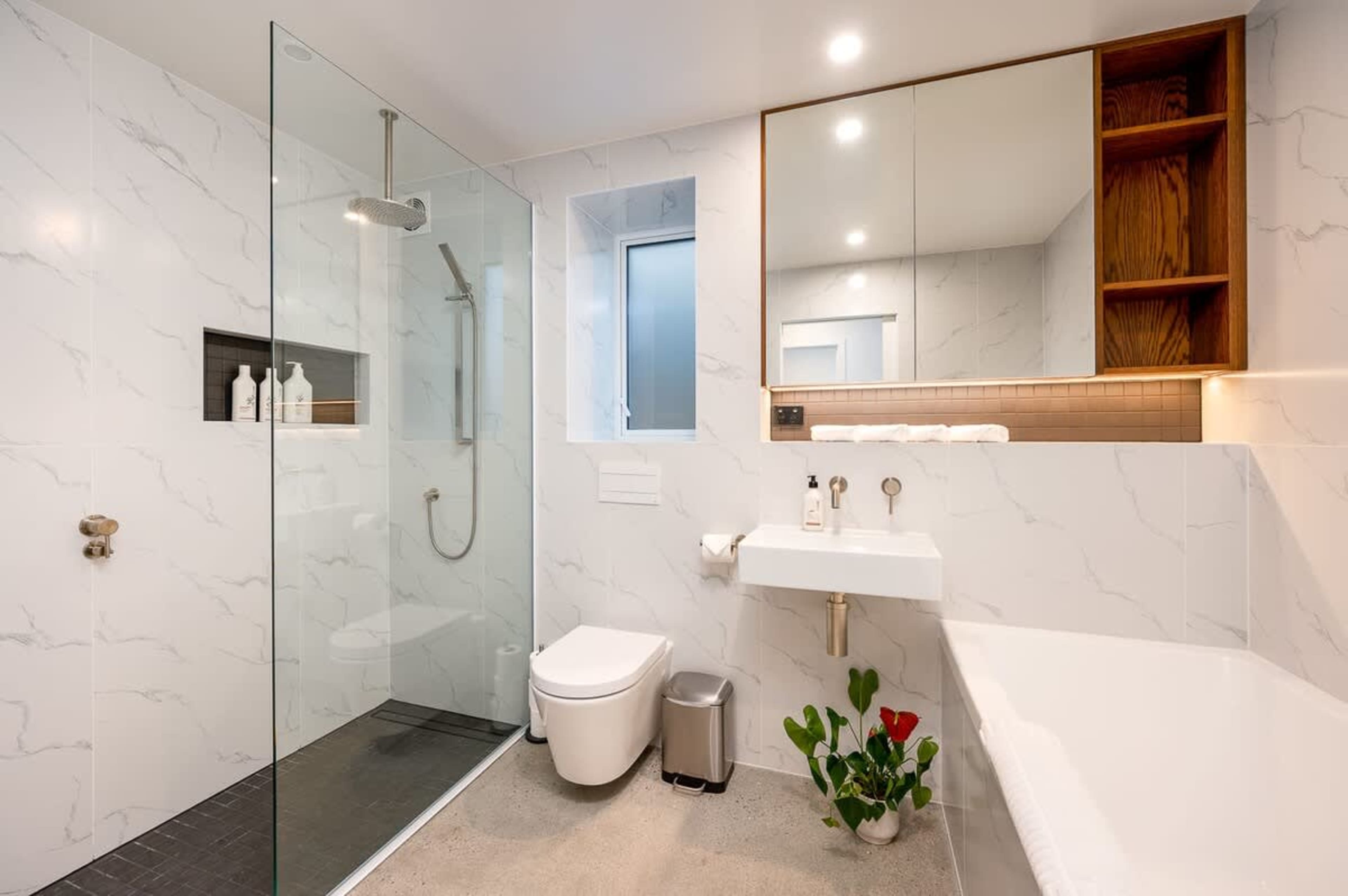 The shared bathroom is equipped with a relaxing bathtub, a walk-in shower, and premium amenities including heated floors and towel rails, providing a spacious and luxurious experience for guests.