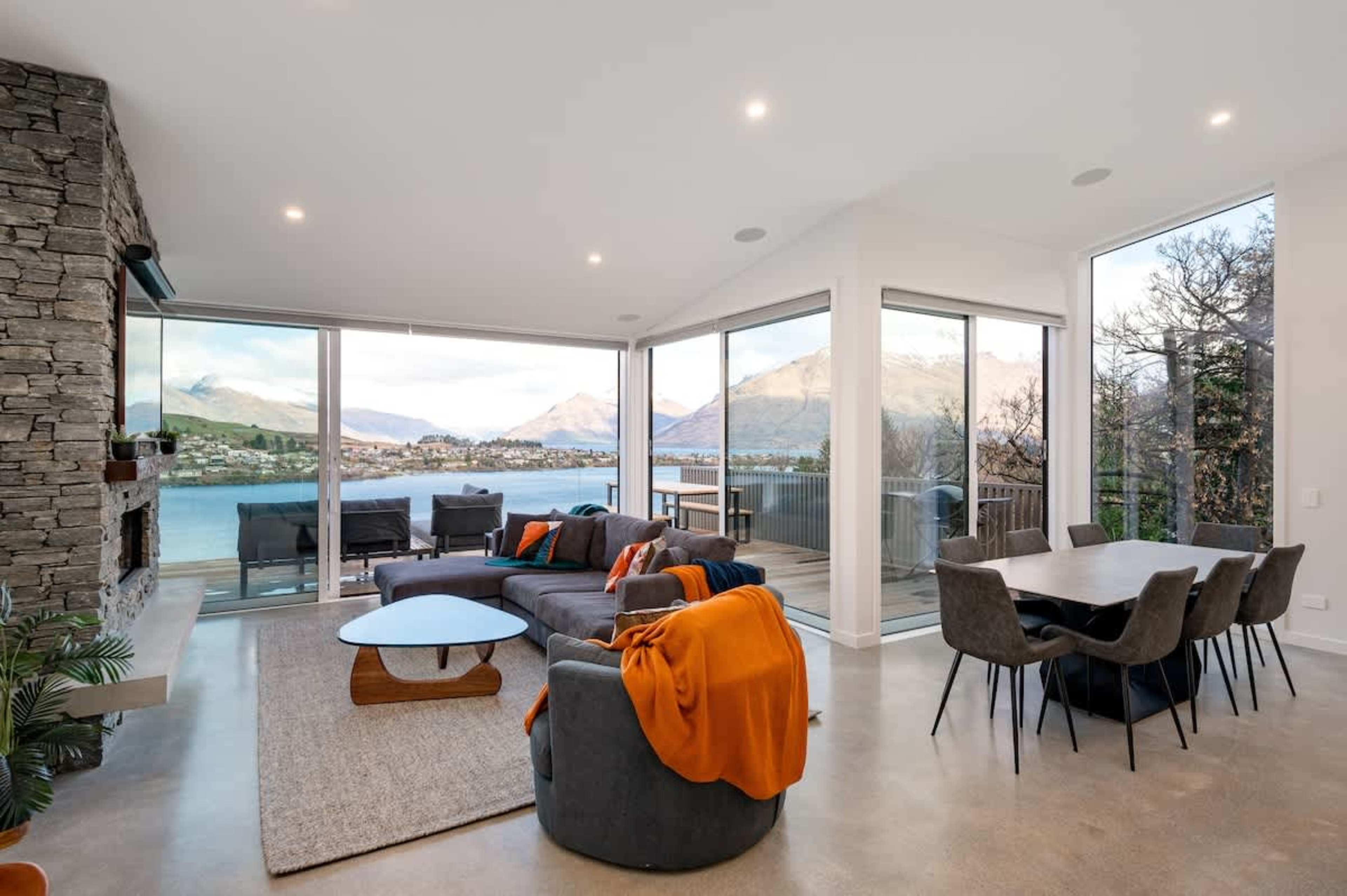 The spacious living room features a cozy gas fireplace, large windows framing stunning views of Lake Wakatipu and the surrounding mountains, making it the perfect place to relax and unwind.