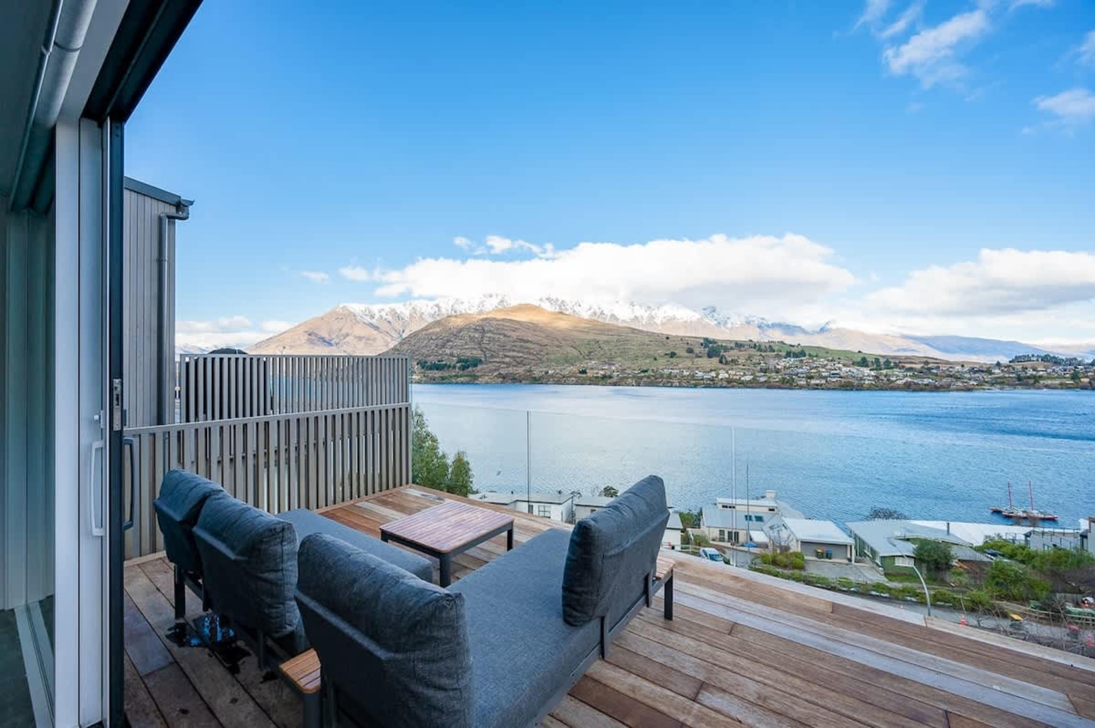 The balcony offers stunning views of the lake and mountains, complete with a BBQ and seating area, perfect for enjoying a glass of wine while taking in the breathtaking scenery.