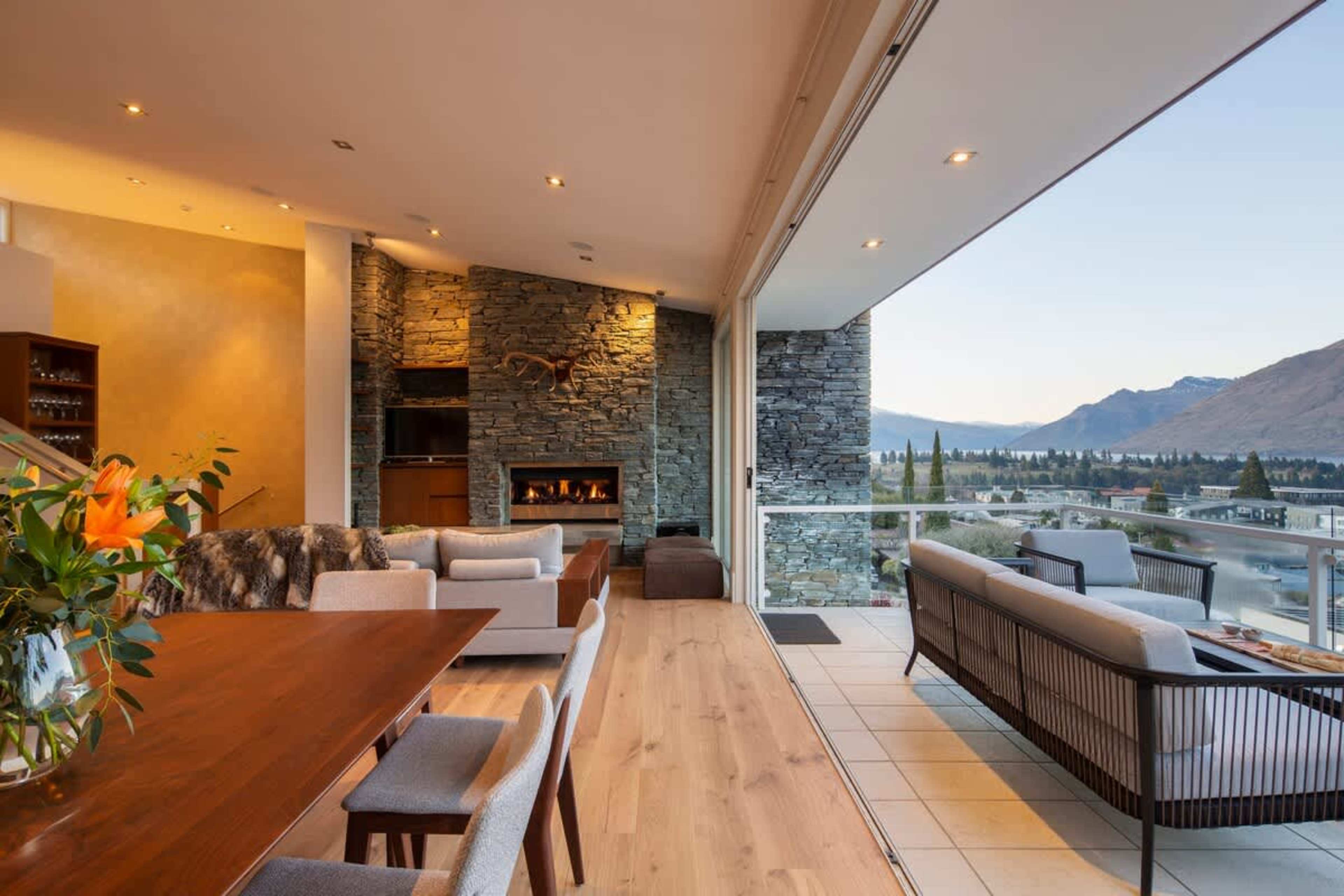 Spacious and Inviting: Relax in the open-plan living room with a cozy gas fireplace, plush seating, and expansive windows showcasing stunning lake views.