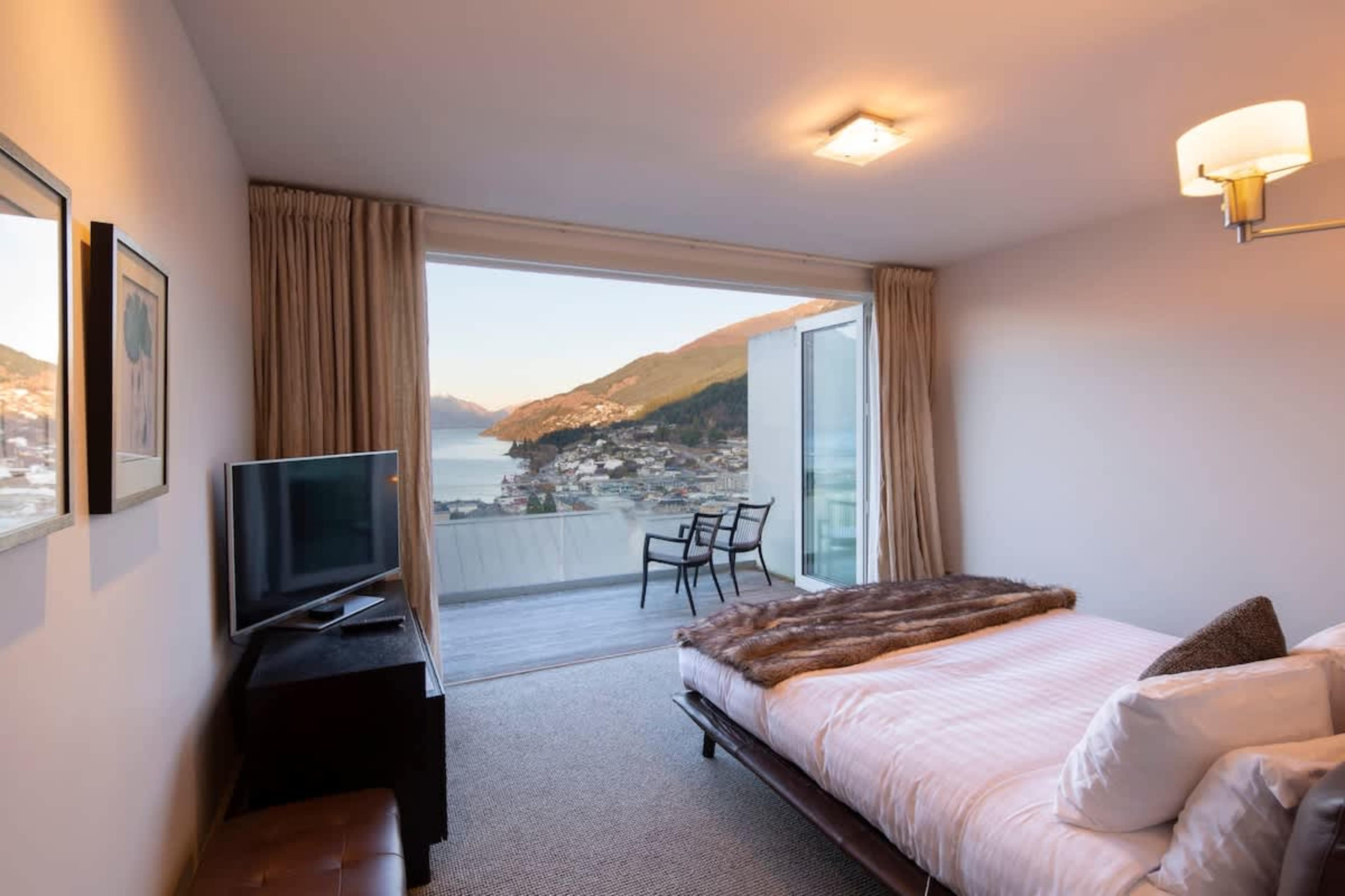 Peaceful Second Bedroom: Cozy and inviting, this bedroom features access to a private deck with breathtaking lake and mountain views, perfect for unwinding in tranquility.