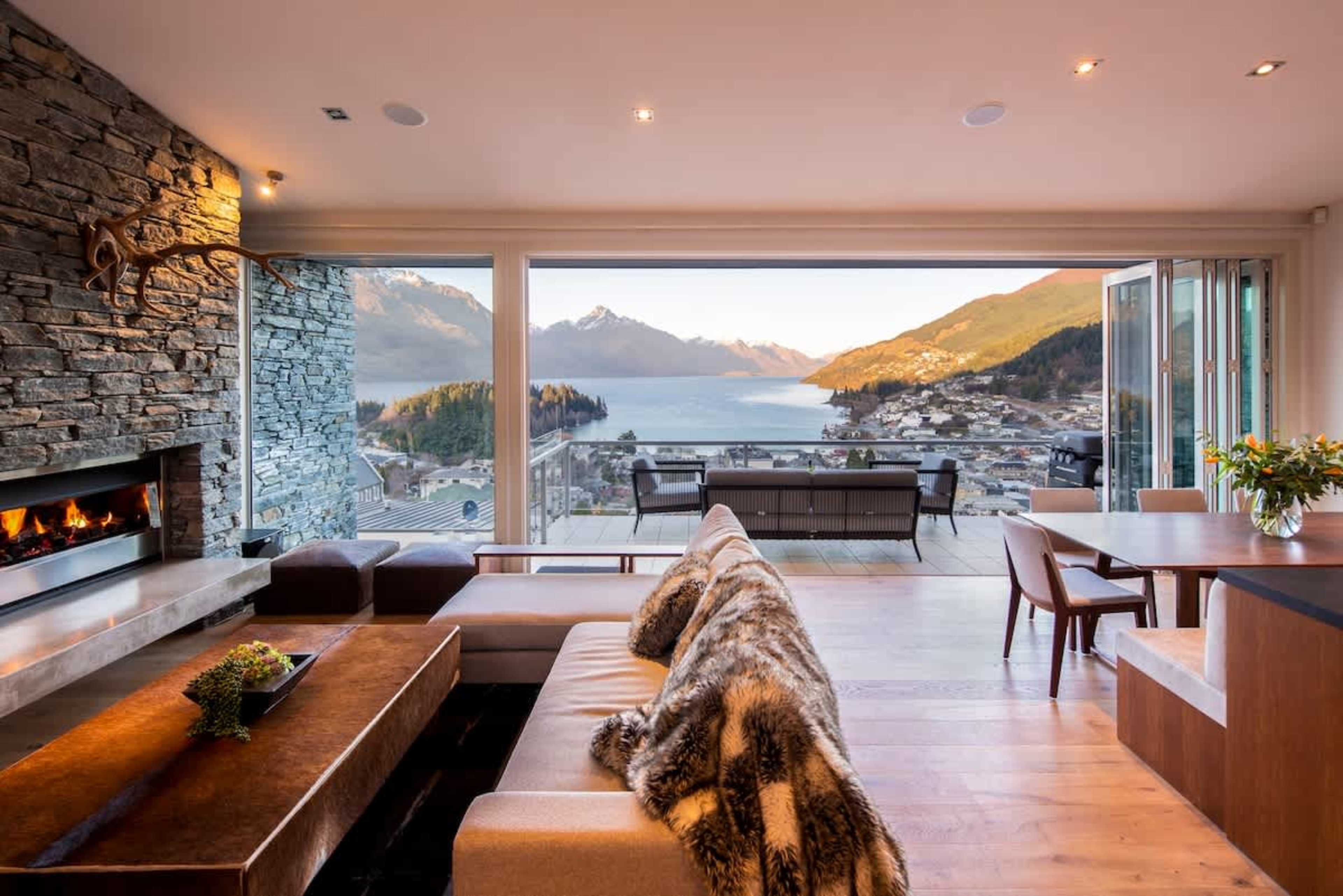 Living Room: Cozy and inviting space with plush seating for six, a gas fireplace, and large windows showcasing stunning lake and mountain views.