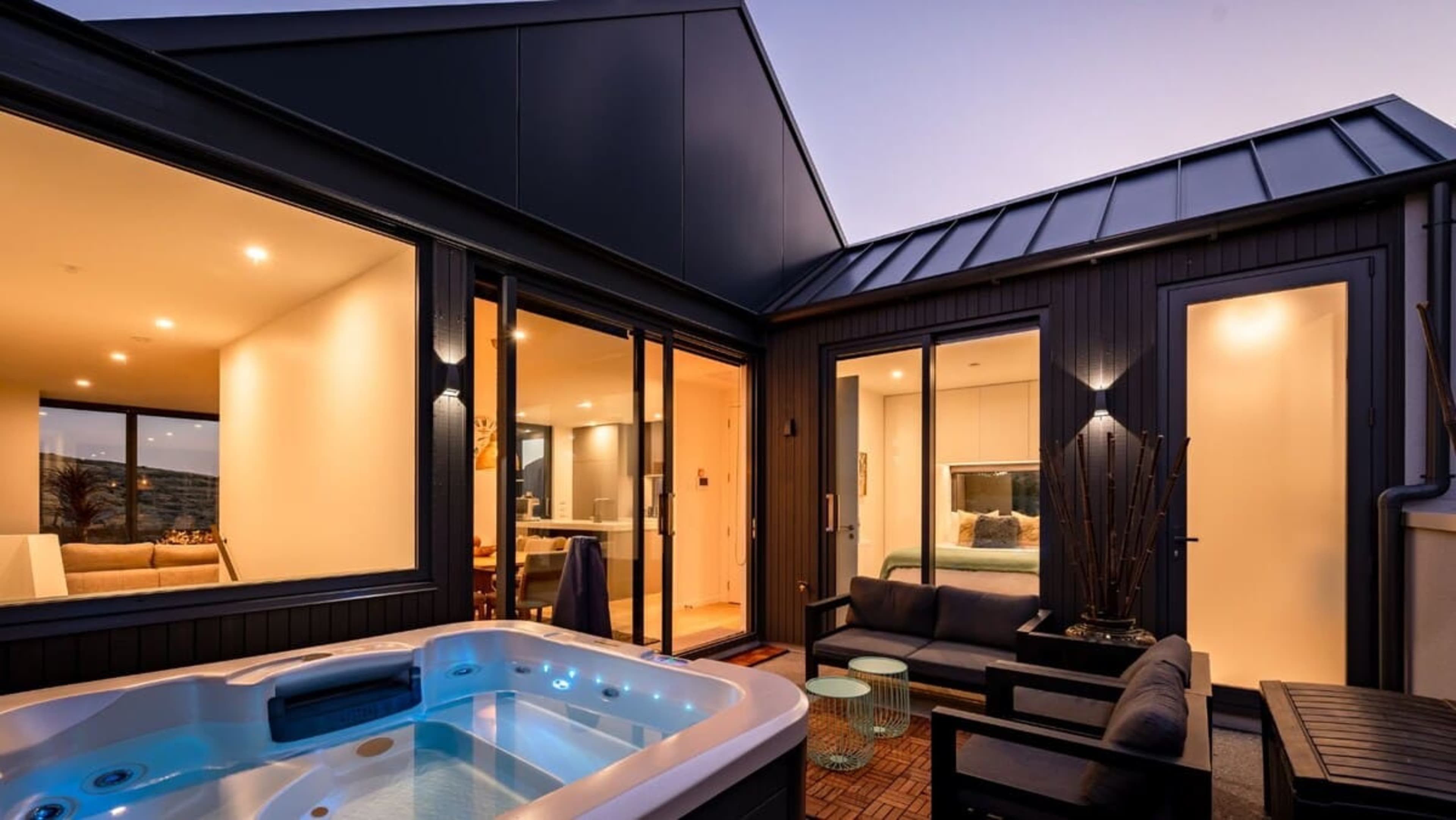 The spacious back deck features a luxurious hot tub, outdoor dining area, and a BBQ, creating an ideal space for both relaxation and entertaining.