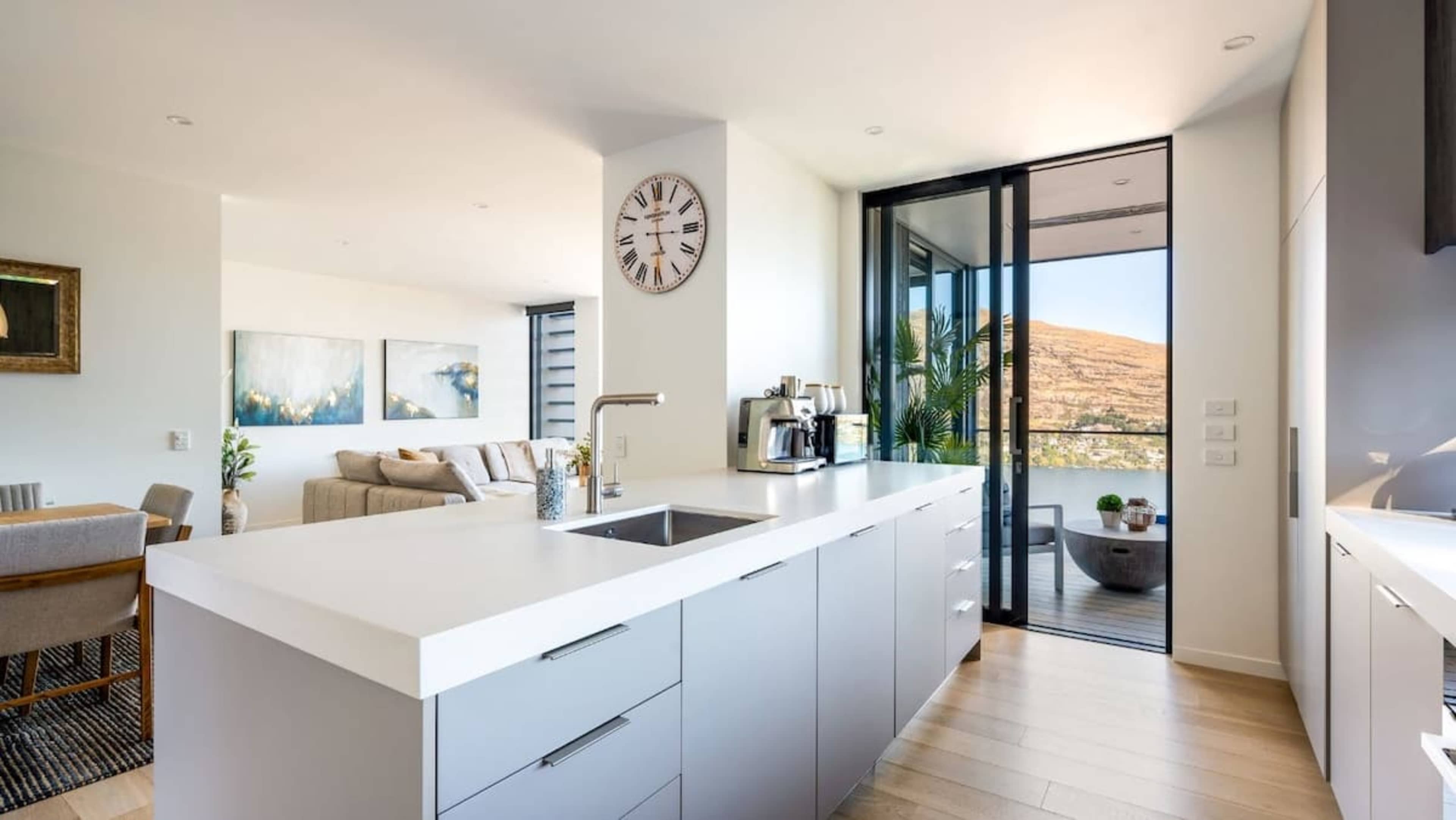 The sleek, modern kitchen is equipped with high-end appliances, ample counter space, and a coffee machine, making it ideal for preparing gourmet meals or enjoying a coffee break."