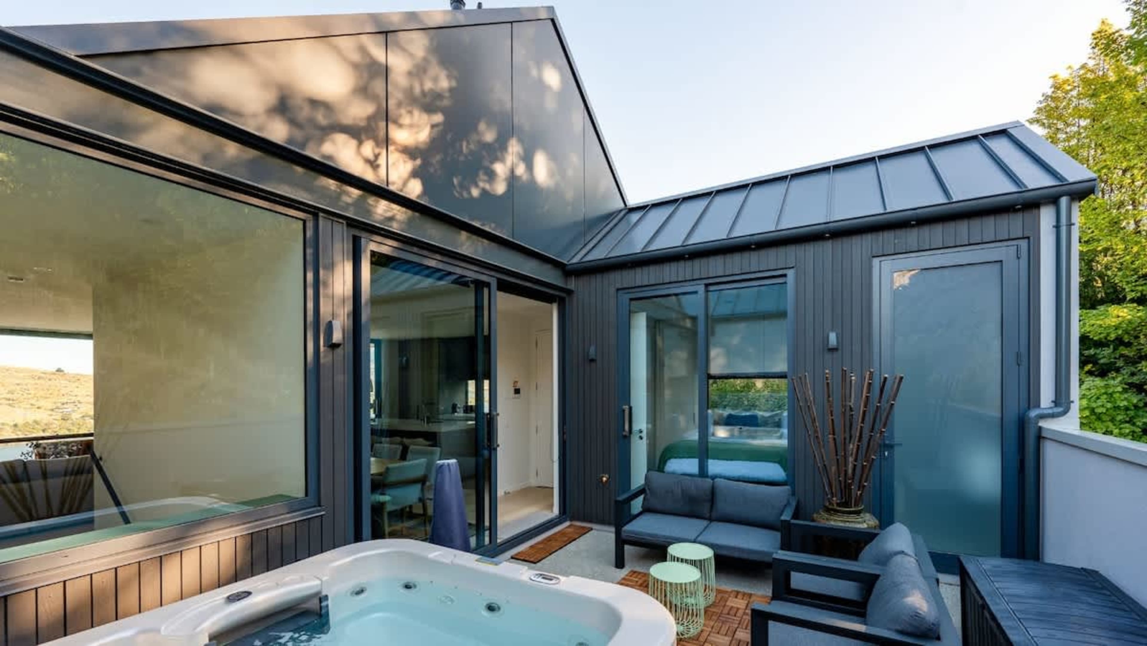 This inviting back deck off the kitchen features a hot tub, outdoor dining table, and BBQ, offering the perfect space for dining and relaxation amidst stunning views.