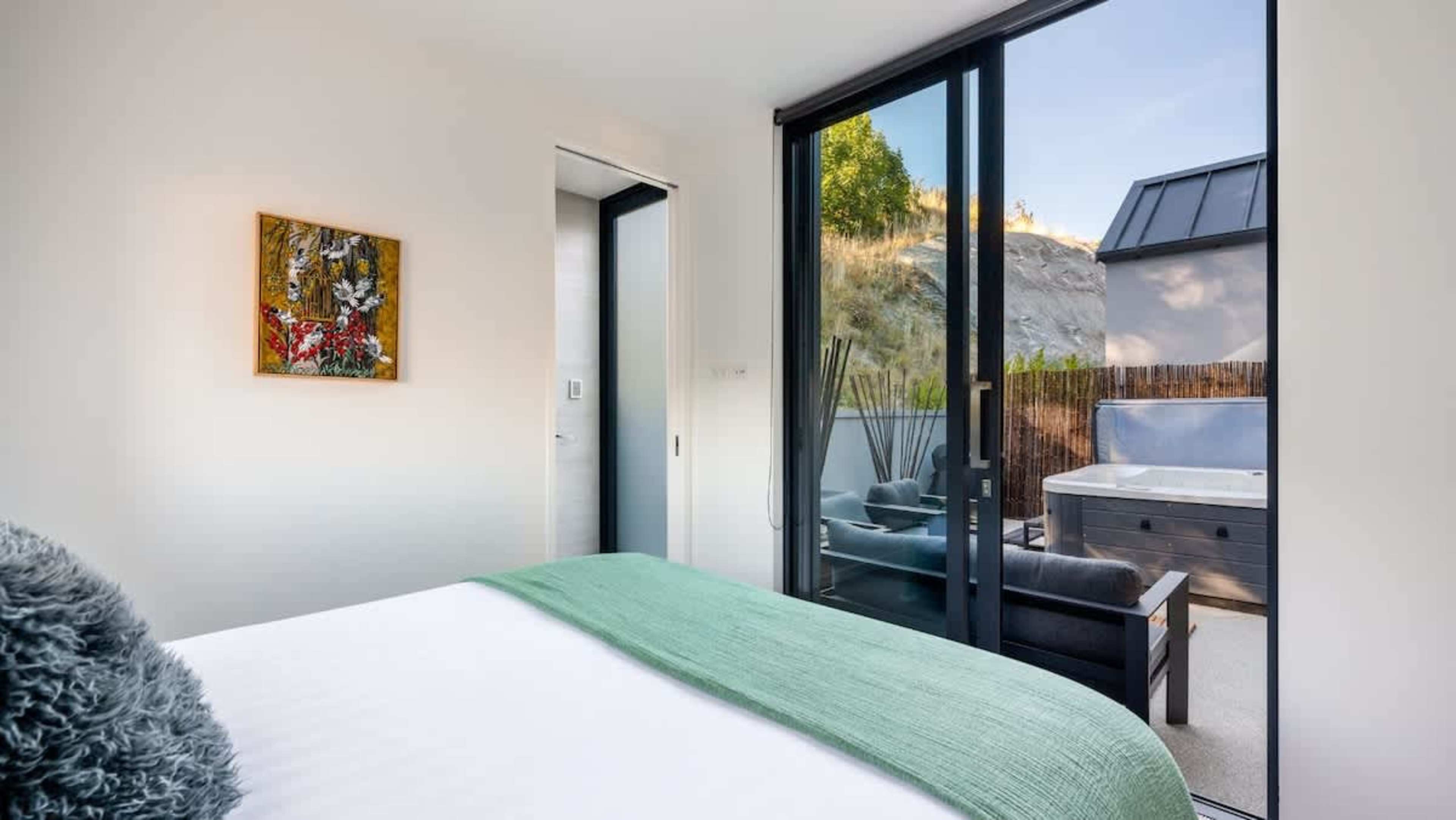 This spacious fourth bedroom features a comfortable king-sized bed, an ensuite with a rain shower, and stylish decor, offering both comfort and privacy.