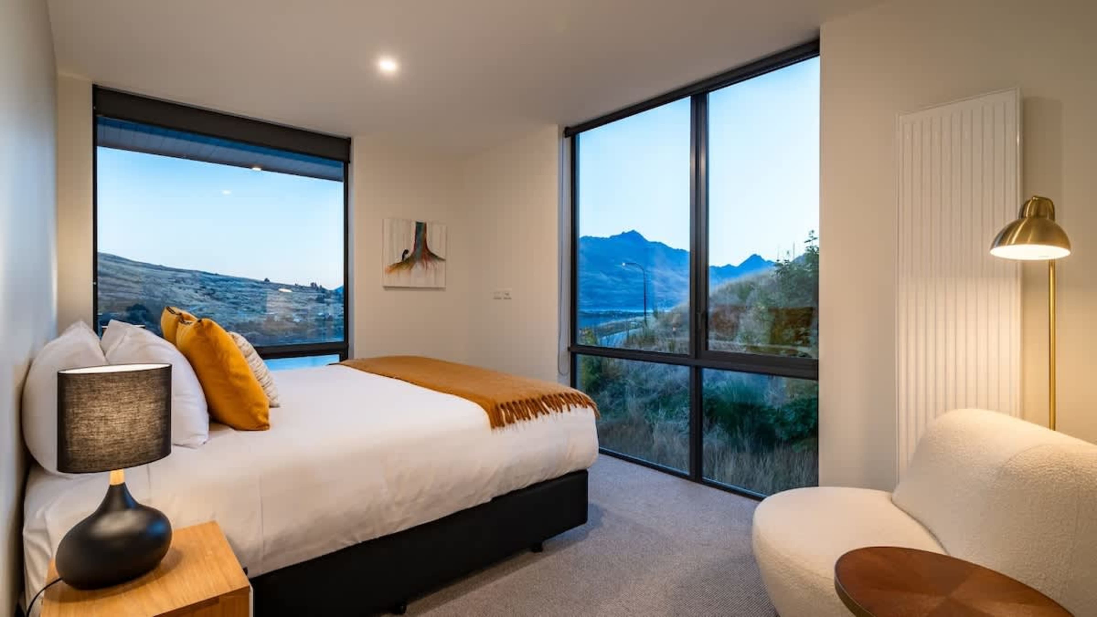 The master bedroom features a luxurious king-sized bed, an ensuite with a walk-in shower, and a spacious wardrobe, all set against stunning lake and mountain views.