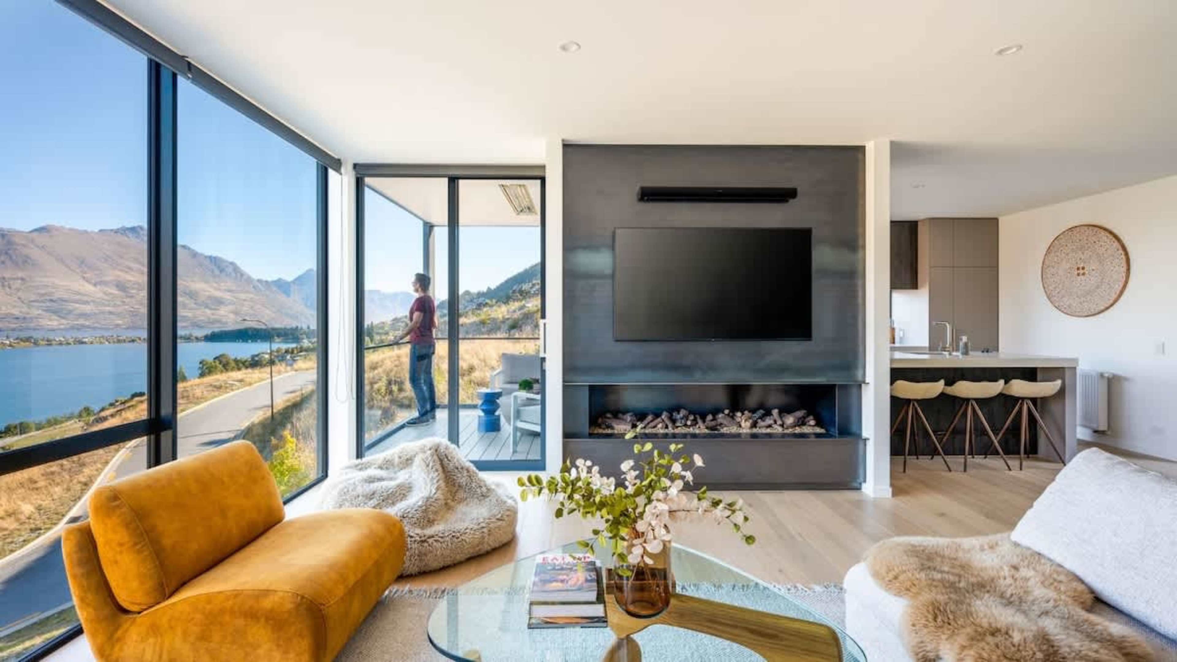 With floor-to-ceiling windows and heated floors, the elegant living room of this super-luxe 4-bedroom villa allows you to enjoy incredible lake and mountain views, all while cozying up by the indoor fireplace.