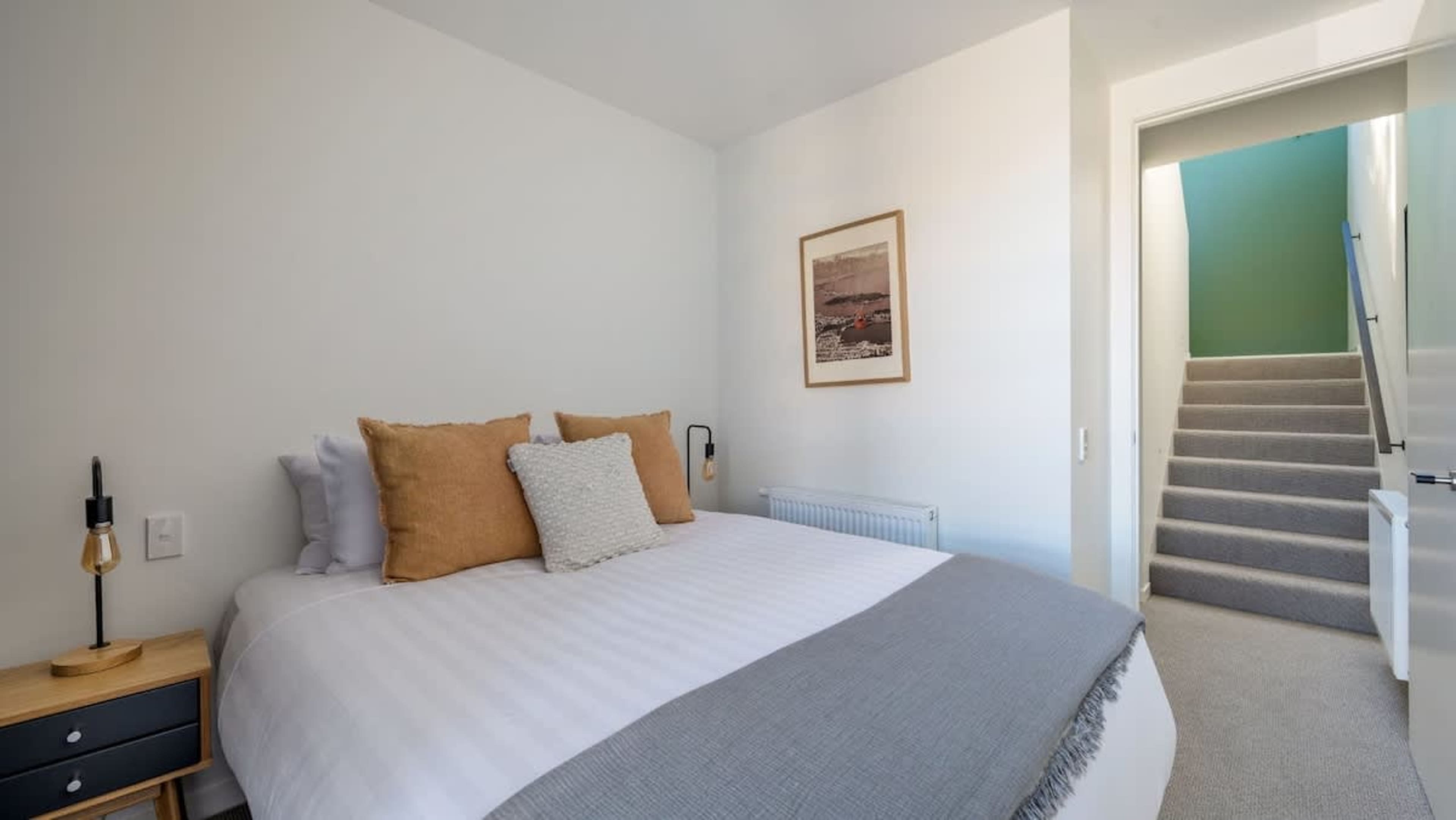 The second bedroom features a comfortable queen-sized bed, tasteful decor, and stunning views of Lake Wakatipu and the surrounding mountains, offering a peaceful retreat.