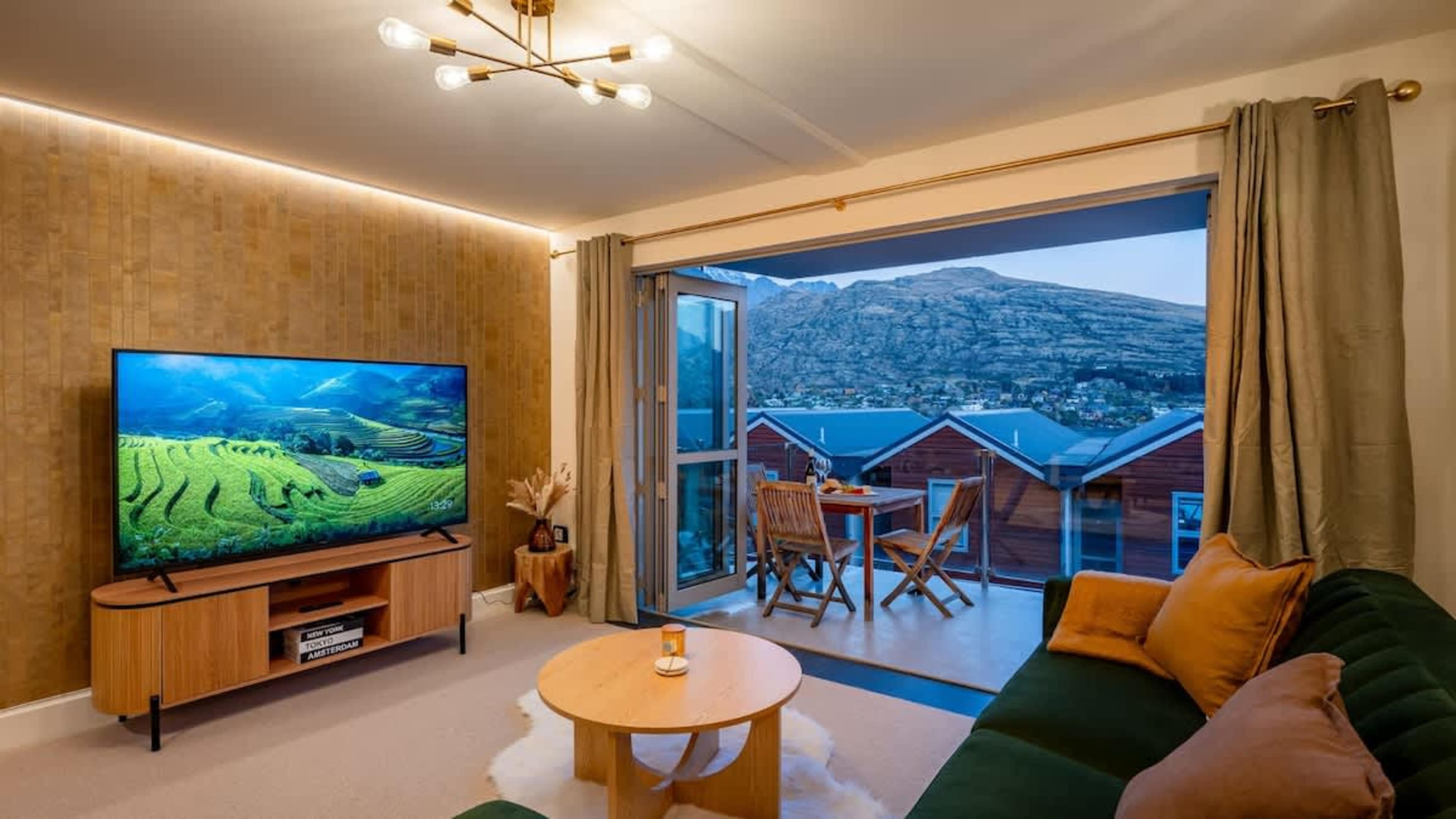 Bright, modern living room with stunning lake and mountain views, cozy seating, and plenty of natural light—perfect for relaxation or enjoying Queenstown's breathtaking scenery.