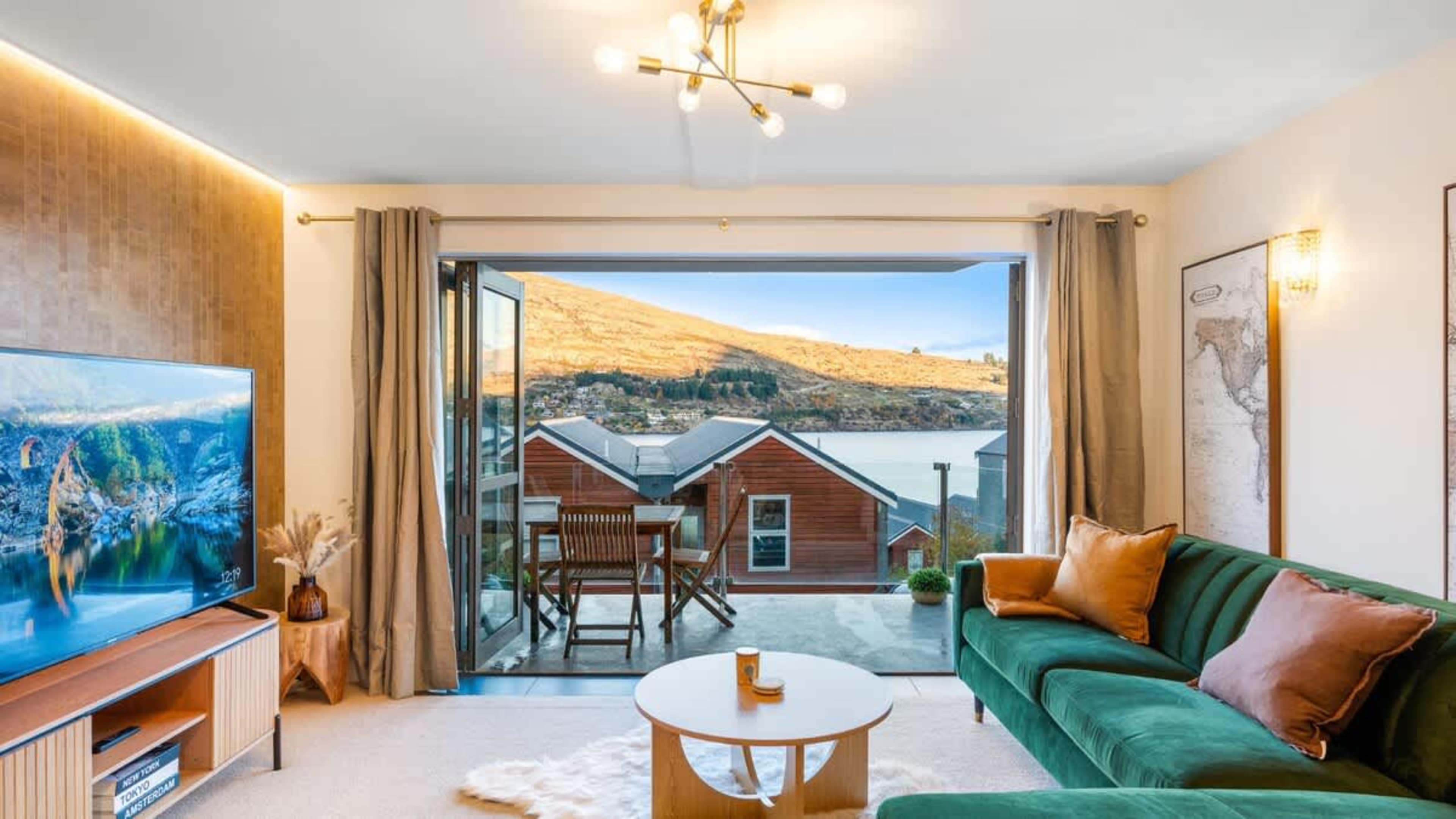 Comfort meets style in this living room with a sofa, entertainment system, and spectacular views of Lake Wakatipu. 
NZ Luxury Travel