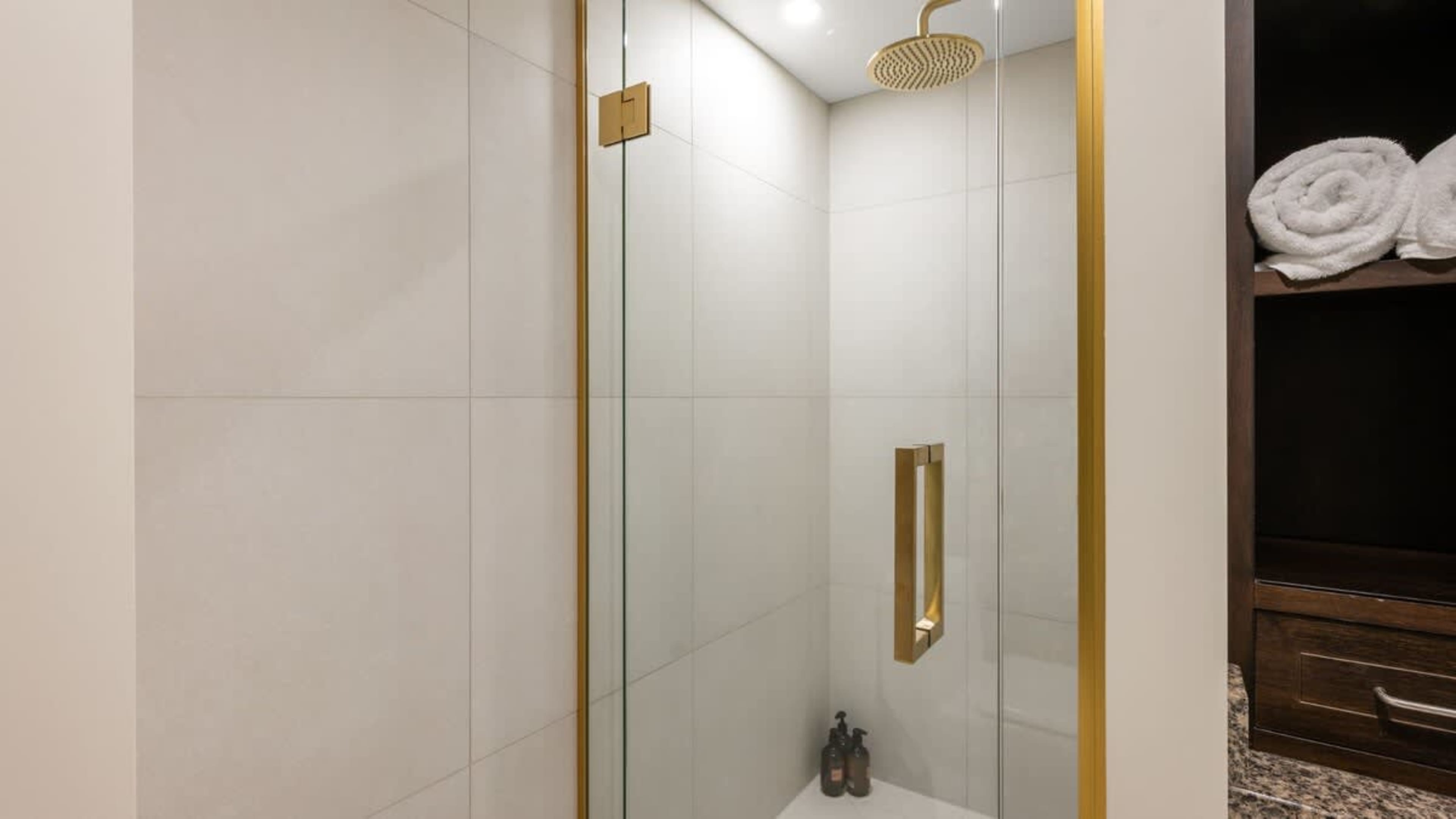 Modern bathroom featuring a walk-in rain shower, premium Ashley & Co toiletries, and elegant finishes for a spa-like experience.