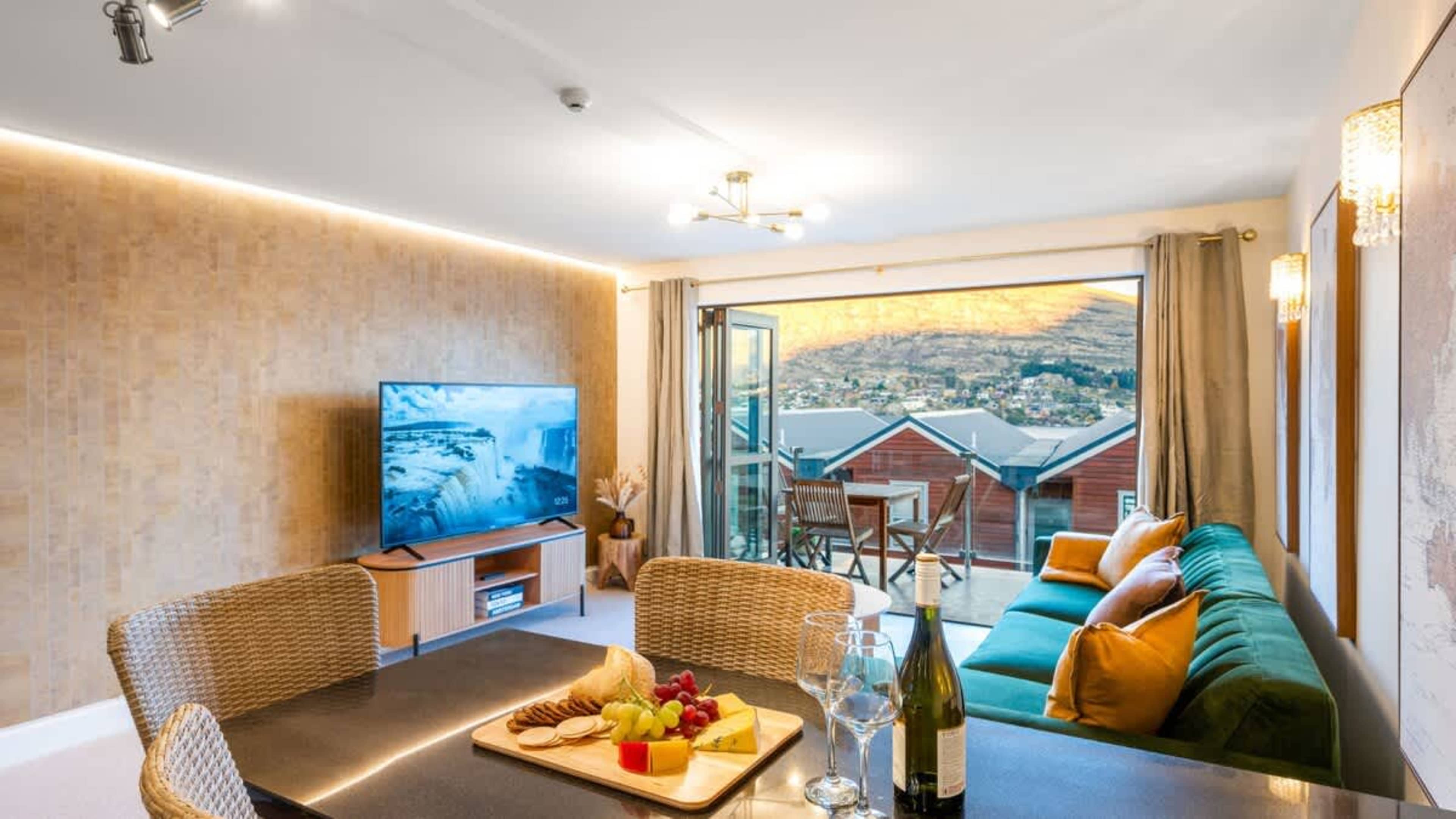Modern living space with floor-to-ceiling windows showcasing breathtaking Queenstown scenery and a warm, inviting atmosphere.