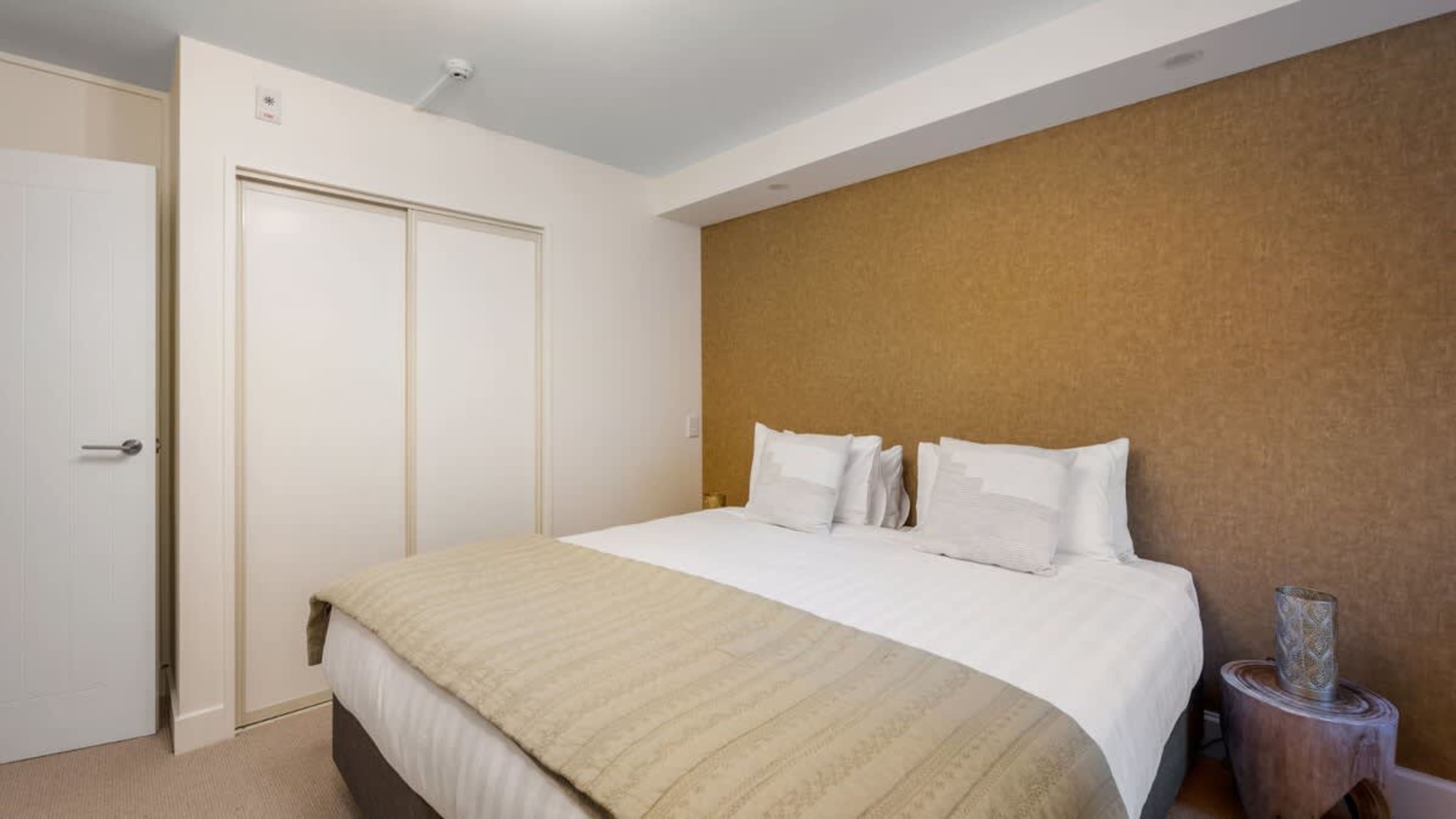 Spacious master bedroom with a luxurious king-sized bed, premium linens, and sweeping lake and mountain views for a serene retreat.