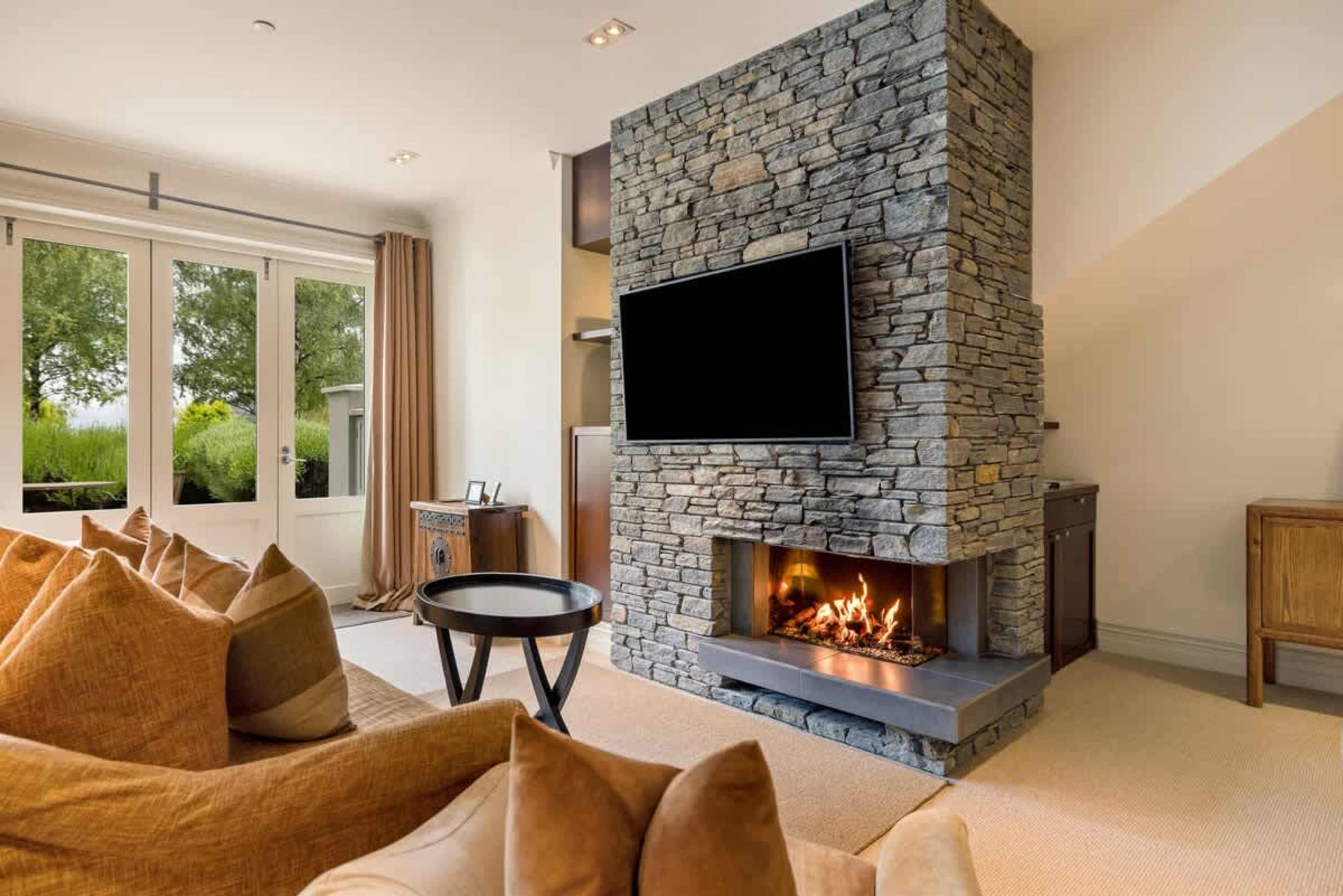 Cozy Living Area with Stunning Views – Relax in this spacious living room, complete with a gas fireplace, air-conditioning, and seamless access to your private patio with breathtaking views of Lake Wakatipu and the Remarkables.