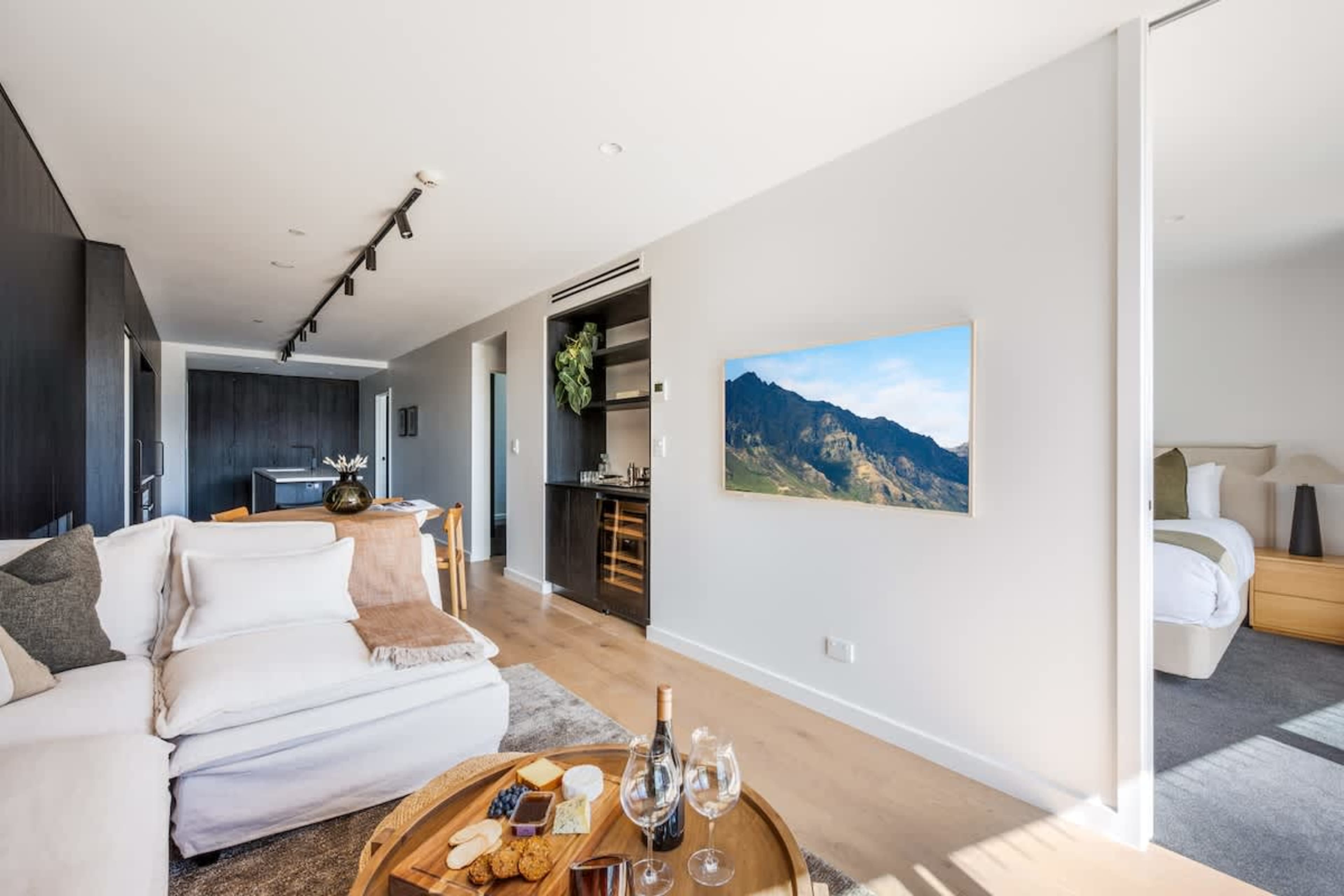 Modern luxury living room, Clubhouse Lane at Jacks Point Golf Course. Epic panoramic views of The Remarkables mountains and Lake Tewa, stylish alpine decor, oak floors, vaulted ceilings, fireplace, floor-to-ceiling windows. Ski & golf haven.