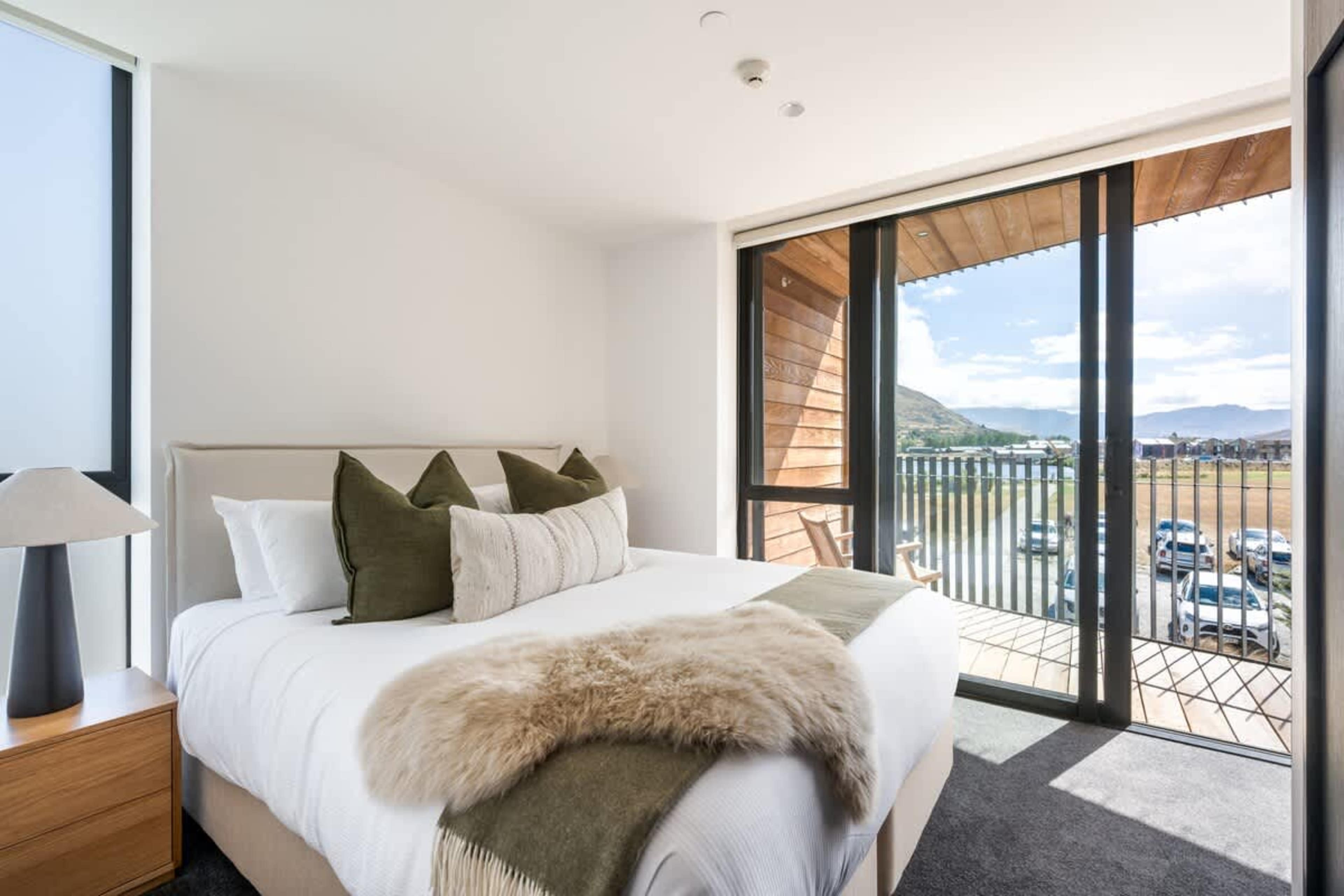 Luxury master bedroom, Clubhouse Lane apartments, Jacks Point Golf Course. King-size Sleepyhead bed, plush bedding, panoramic views of The Remarkables & Lake Tewa, modern alpine style, en-suite access. Queenstown golf & ski retreat.