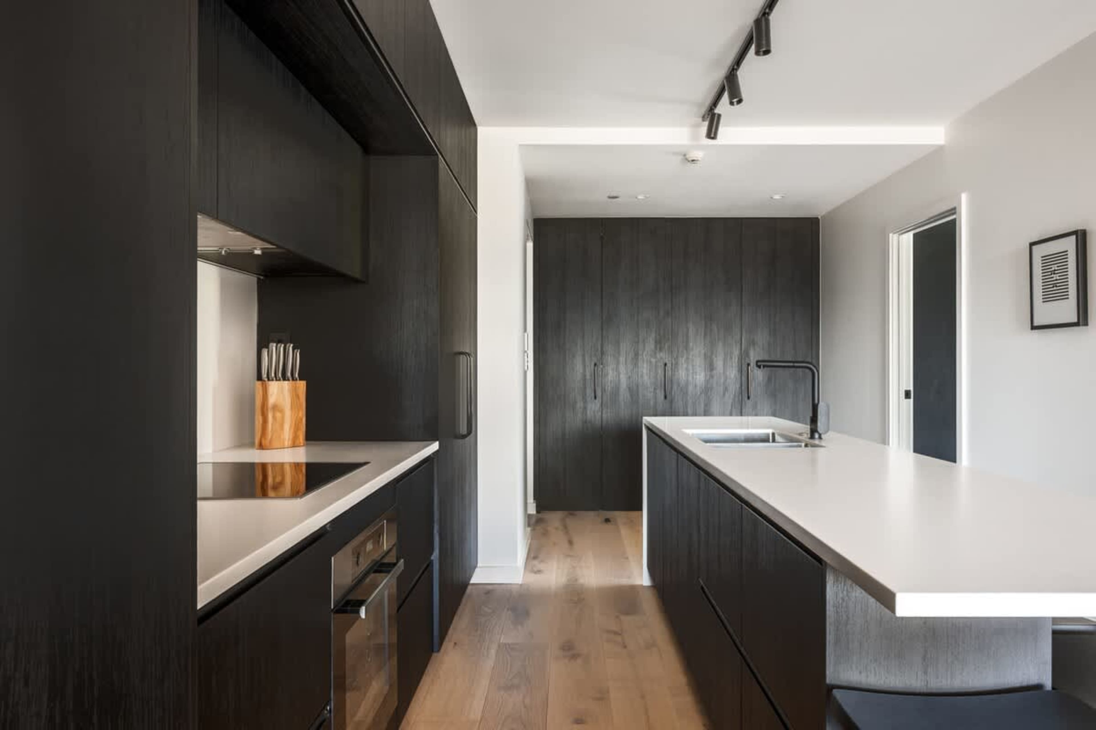 Gourmet kitchen at Clubhouse Lane, Jacks Point Golf Course. Sleek cabinetry, stone benches, premium appliances, open to living area with mountain lake views. Perfect Queenstown golf ski escape.