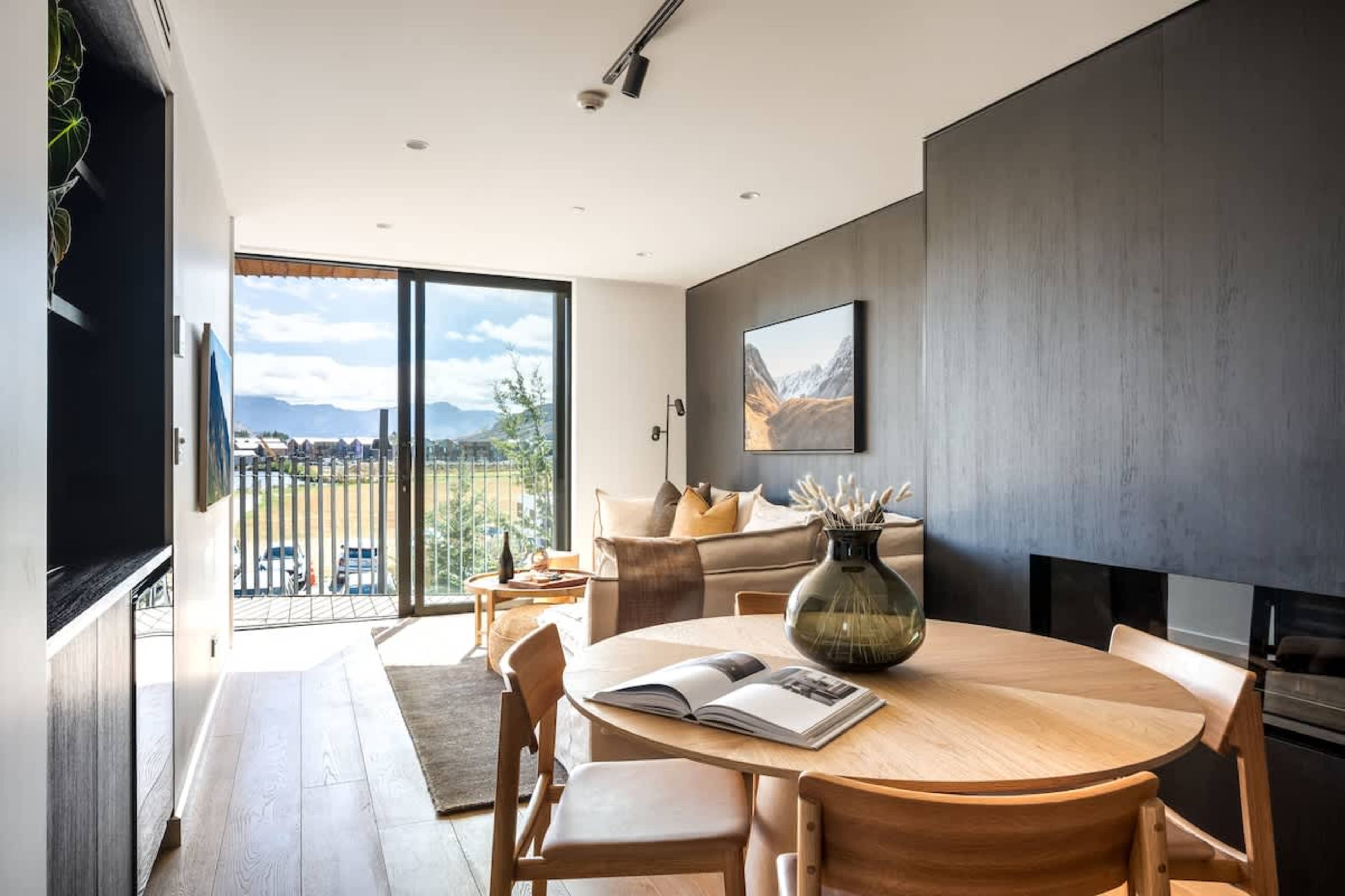 Stylish dining room, Clubhouse apartments Jacks Point Golf Course. Seats 4 comfortably, warm oak finishes, floor-to-ceiling windows framing Remarkables & Lake Tewa views. Ideal luxury ski & golf escape.