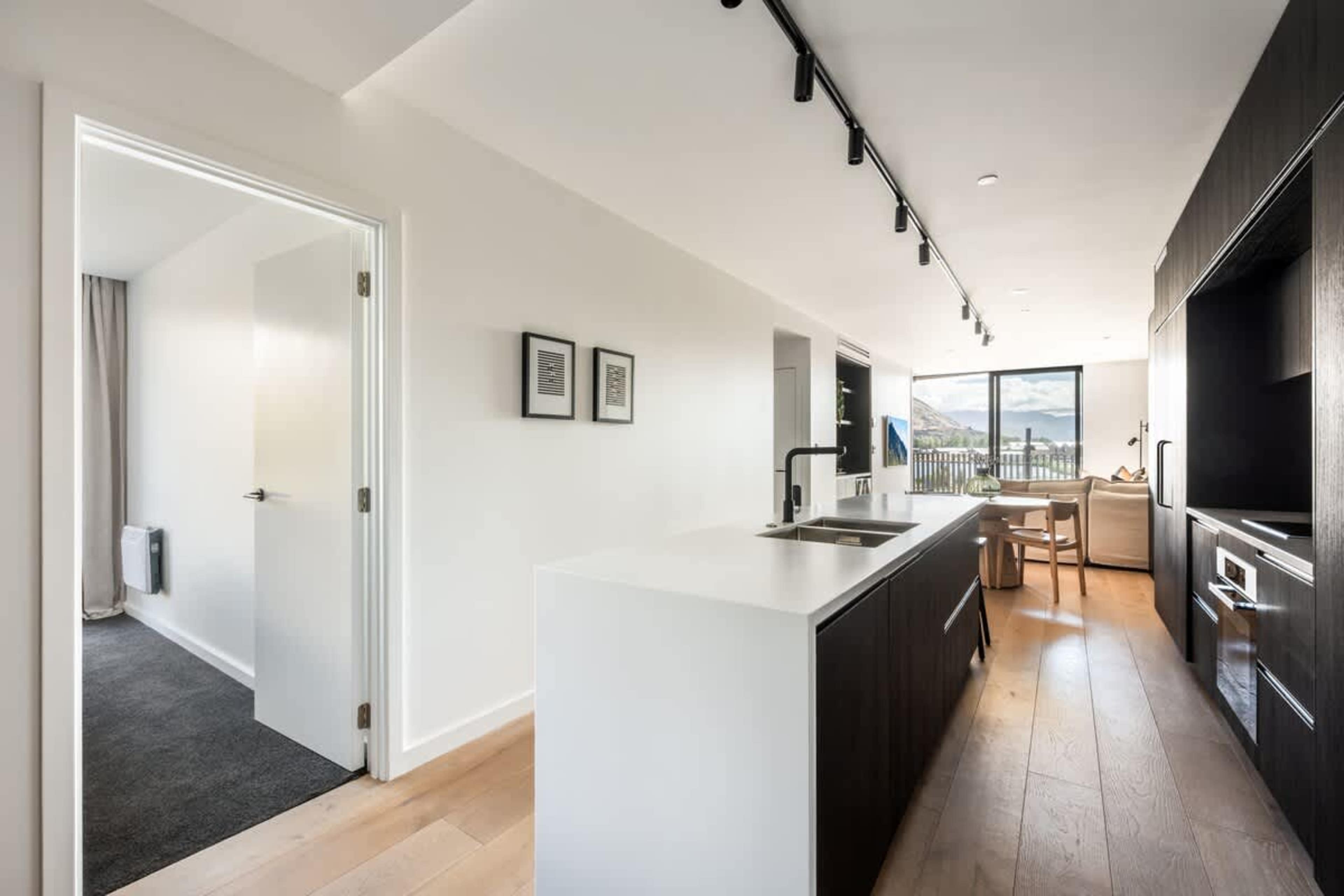 Stylish open kitchen in Clubhouse Lane apartments, Jacks Point. Premium stone benchtops, high-end appliances, breakfast bar, sweeping views over golf course to mountains & lake. Queenstown getaway.