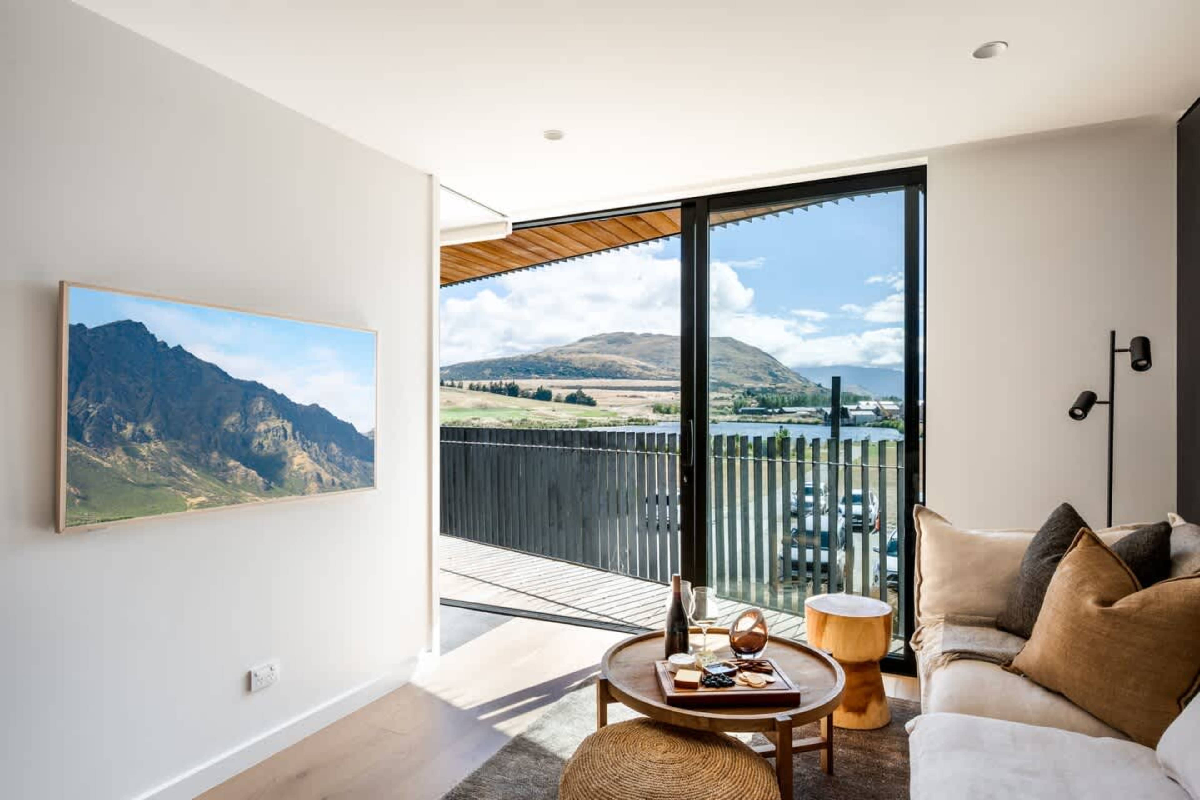 Luxury open-plan living room, Clubhouse Lane, Jacks Point Golf Course. Panoramic Remarkables & Lake Tewa views, modern alpine design, oak floors, vaulted cedar ceilings, feature fireplace, huge windows. Queenstown golf ski escape.