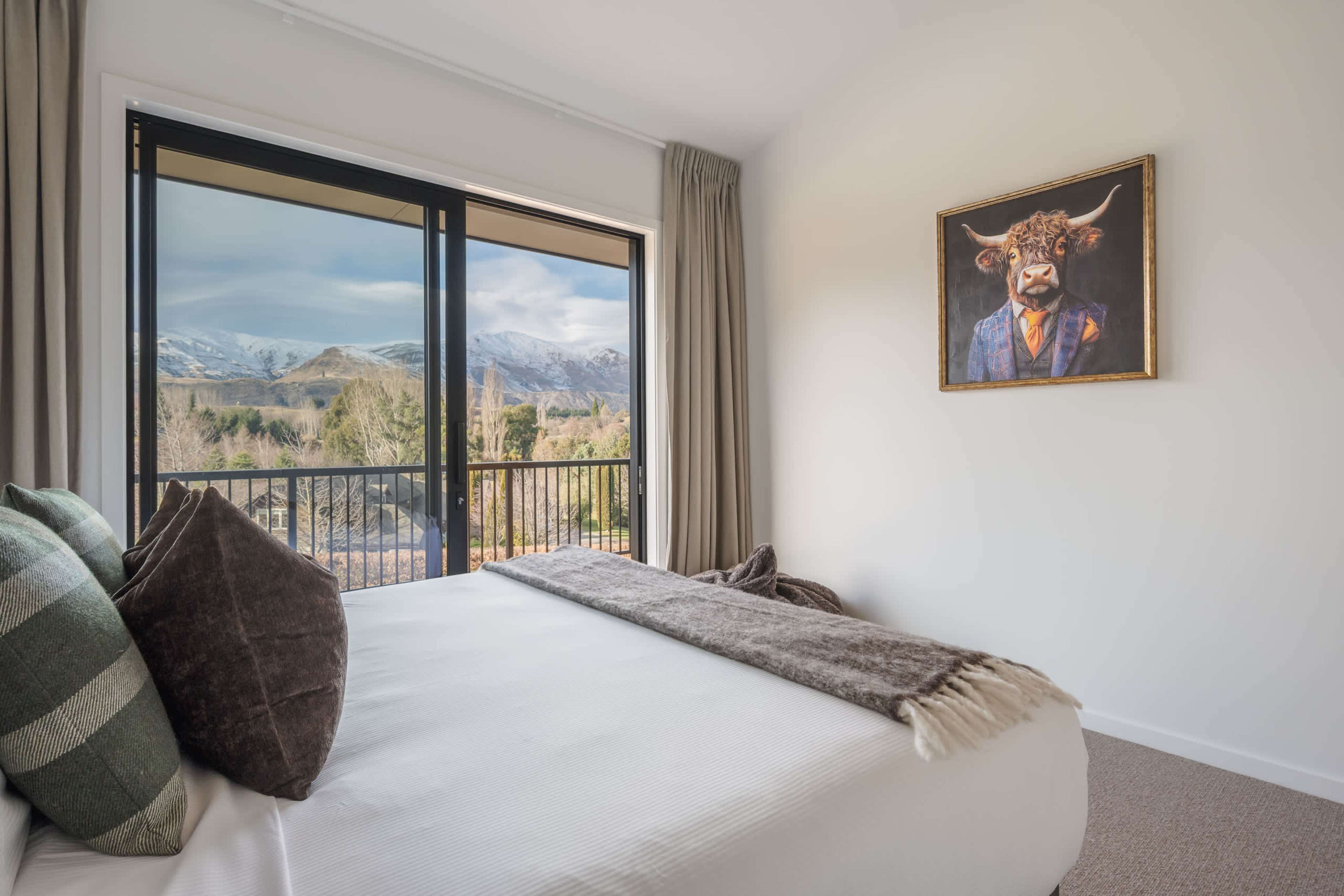 The charming split king second bedroom, with soft, cloud-veiled mountains rolling out beyond the deck.