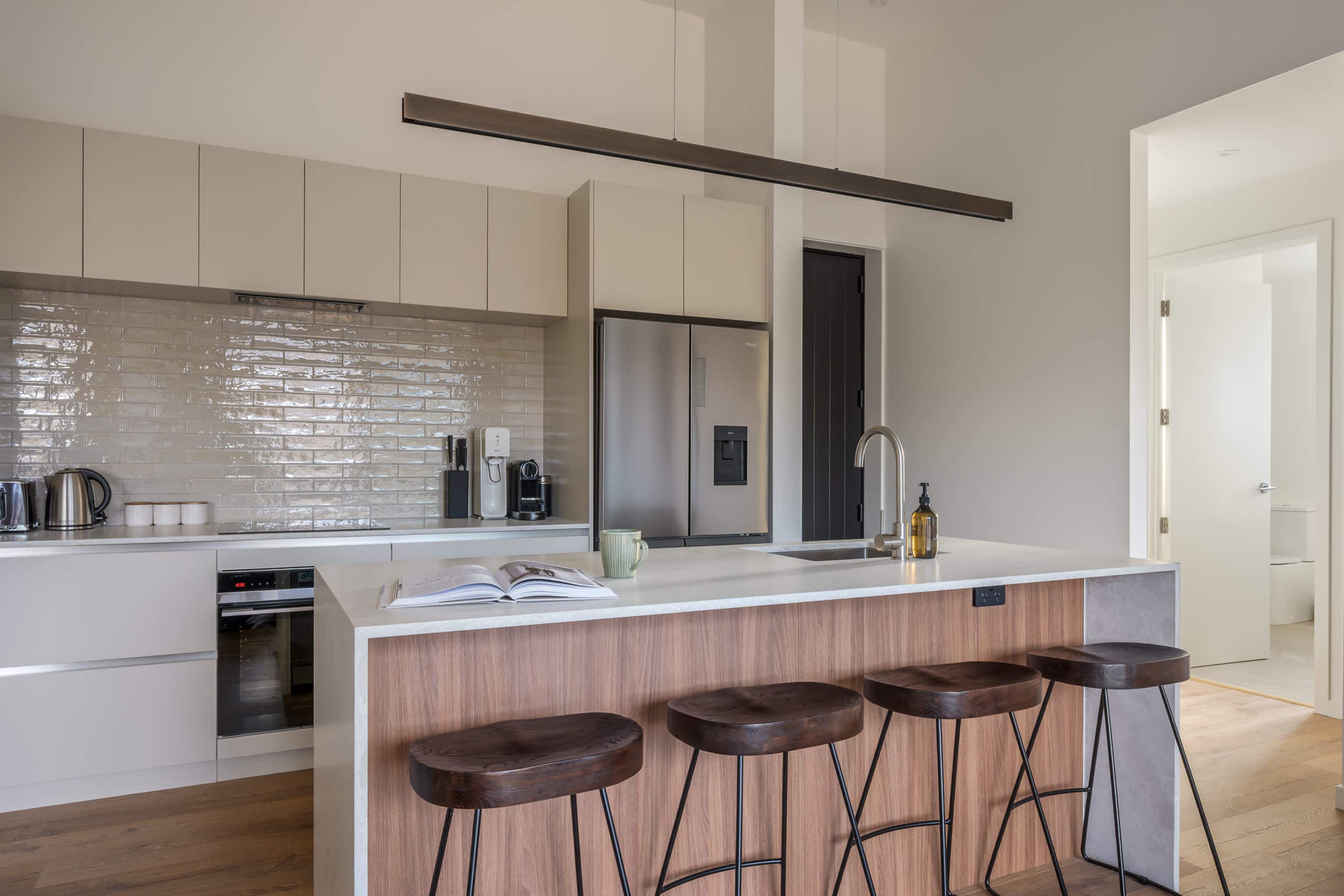 A sleek, fully equipped kitchen, with a walnut island and stools made for lingering over coffee.