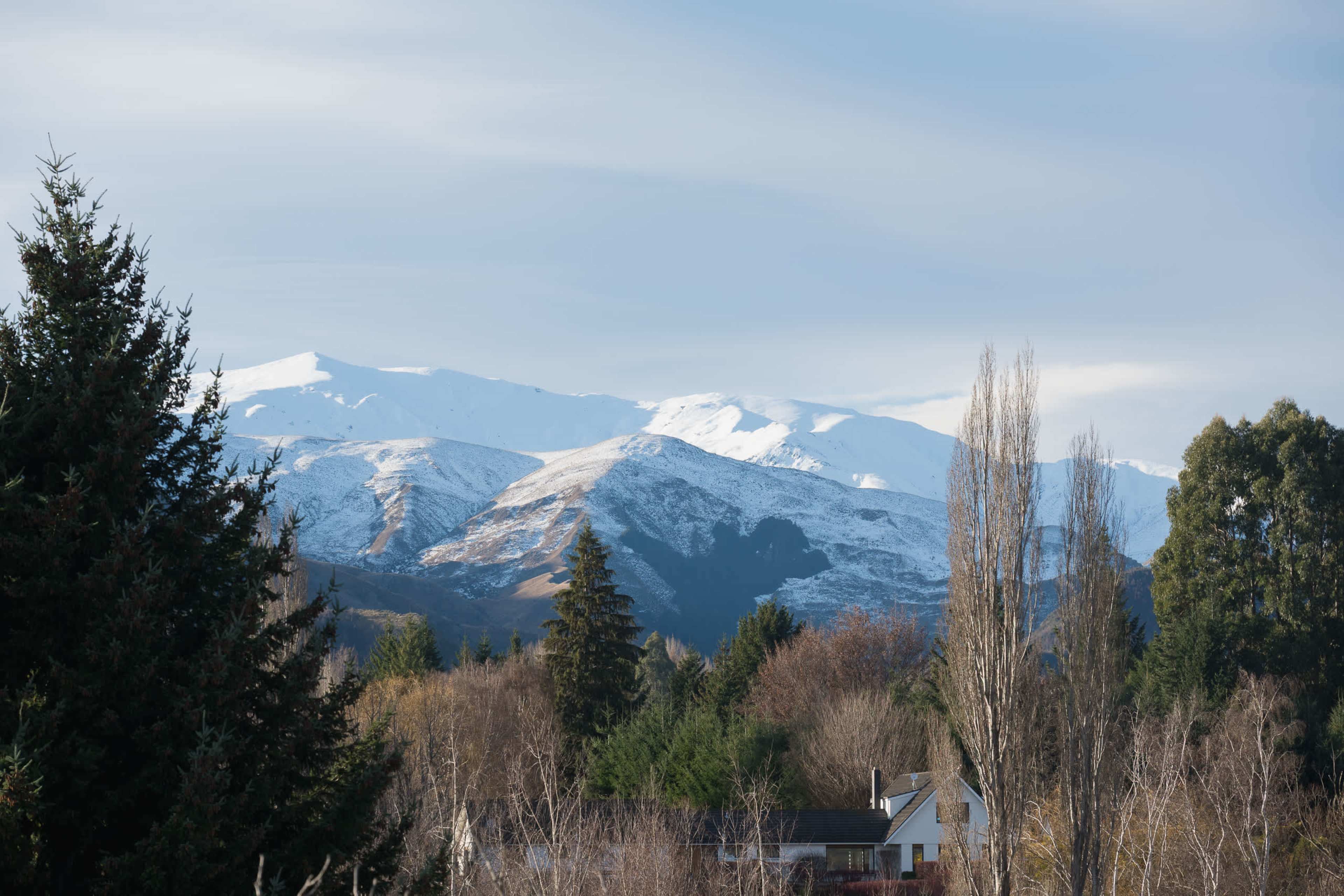 The snow-capped mountains, glimpsed across the tranquil, tree-lined grounds.