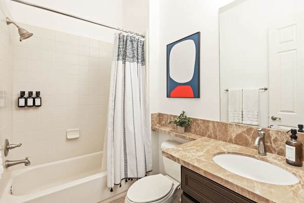 Shared bathroom with tub-shower combo and granite vanity for easy guest use.