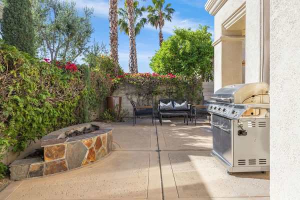 Covered patio with gas grill and seating creates the perfect outdoor dining setup.