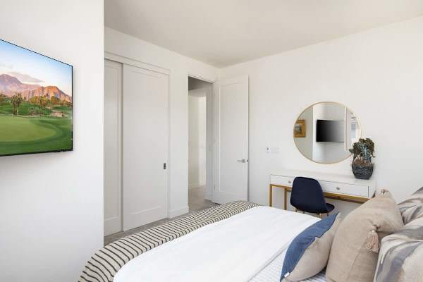 Round mirror and golf art welcome you—second bedroom feels polished and thoughtfully designed.