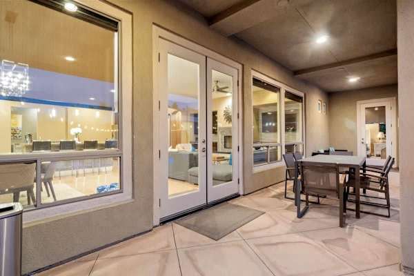Covered dining patio lit up at night—gather here for meals with pool and fire pit steps away.