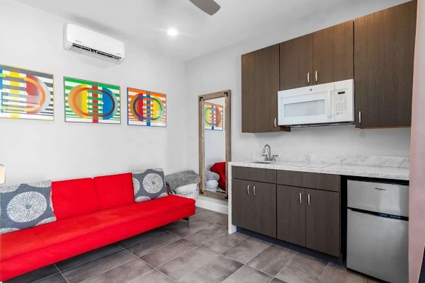 Separate casita with red futon and kitchenette—guests enjoy total independence in this studio space.