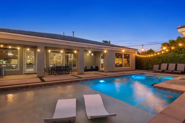 String lights glow above heated pool at twilight—ledge loungers and spa invite evening relaxation.