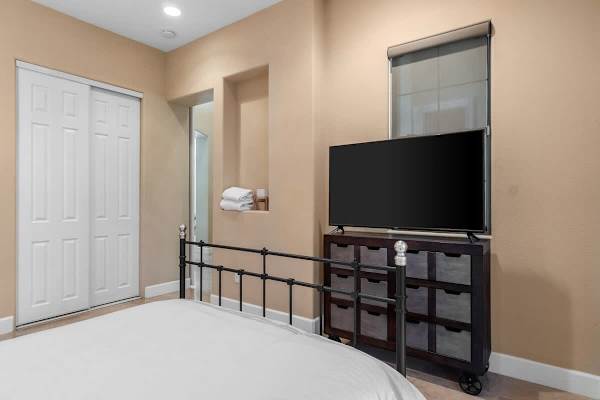 Guest bedroom with wall-mounted TV—metal frame bed and dark wood furniture keep it simple.