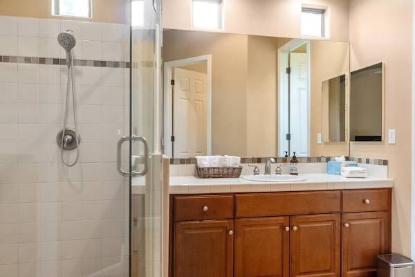 Guest bath with walk-in shower—wood vanity and dual sinks serve second bedroom beautifully.